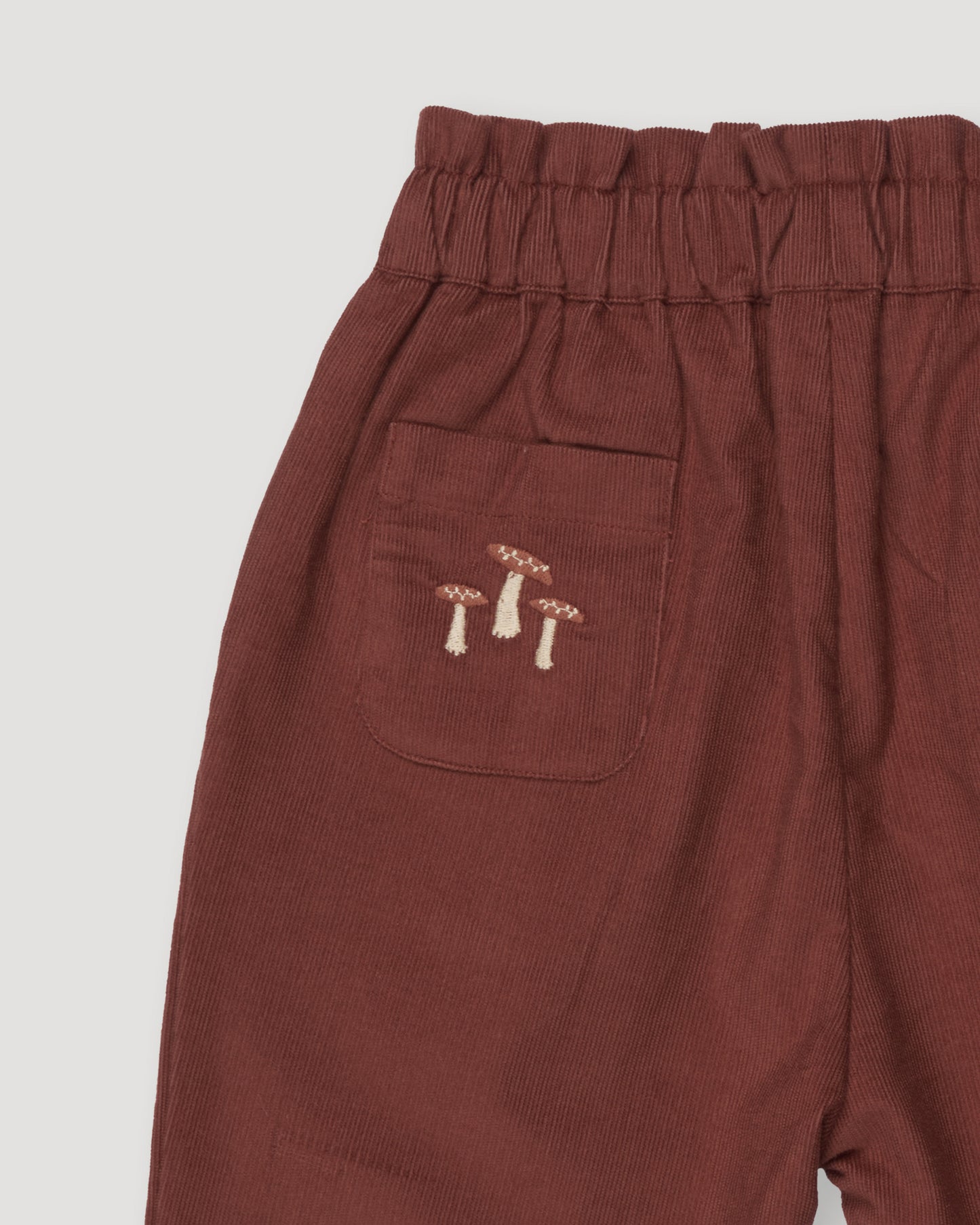 Early Sunday, Adrin Trouser in Caramel color, made from Cotton Corduroy fabric, featuring a relaxed silhouette with a comfortable elastic waistband, shown in a closeup flat-lay view