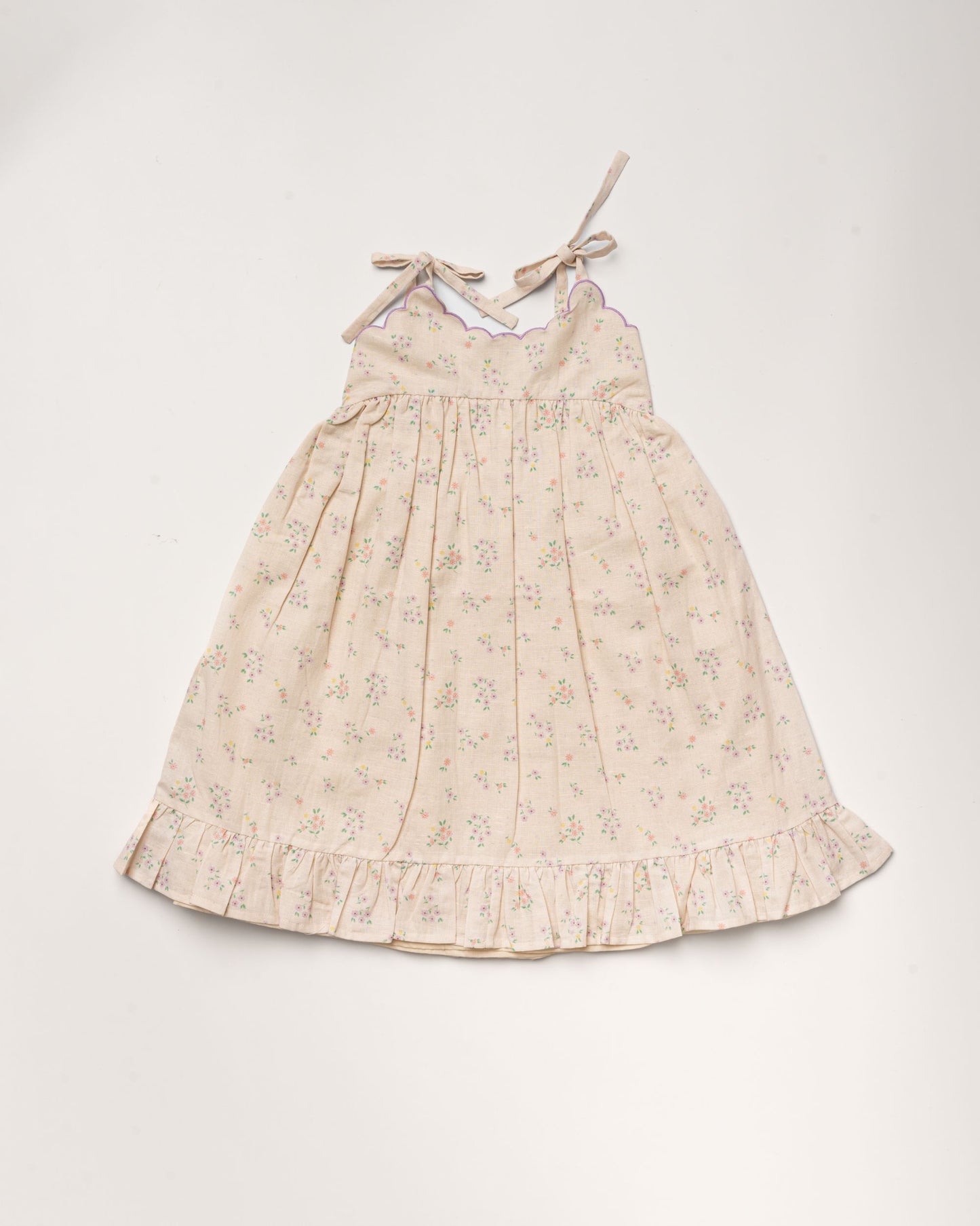 Early Sunday, Alena dress in Painted Bouquet color, made from printed 70% cotton 30% linen fabric, featuring tie-up shoulder straps, gathered flare, and ruffled hem, shown in a front flat-lay view.