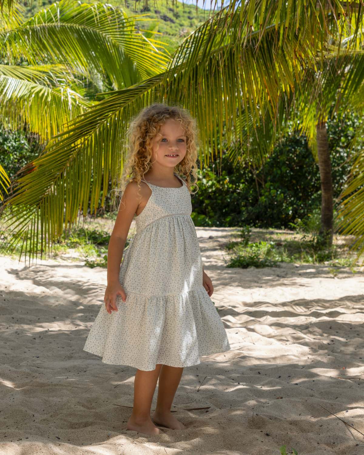 Early Sunday, Alice Dress in Mini Flower print, made from Printed canvas 70% Cotton 30% Linen fabric, featuring sleeveless with adjustable tie-up straps and a tiered silhouette, shown in a front view of a model wearing it