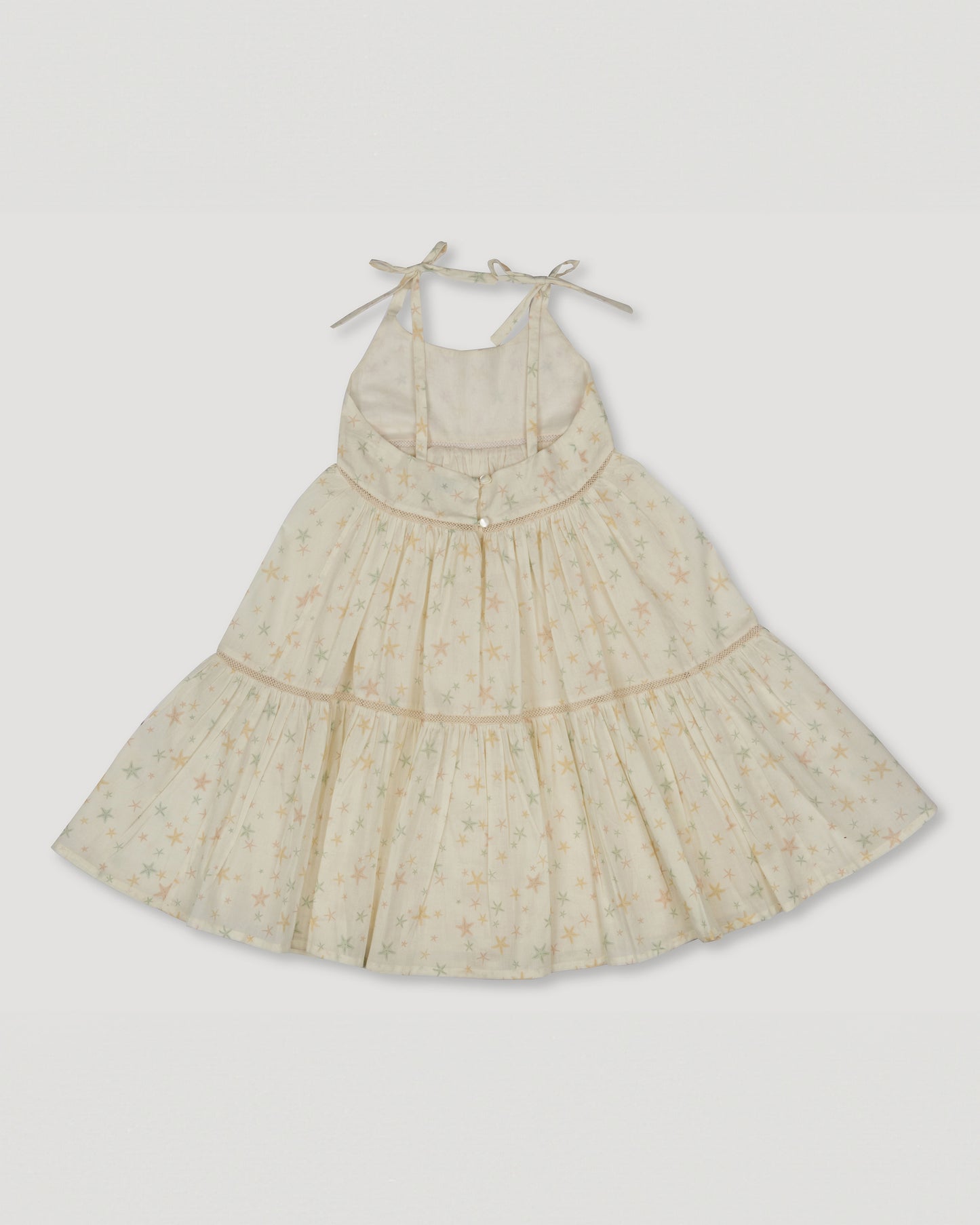 Early Sunday, Alice Dress in Star Fish print, made from Printed Cotton Cambric fabric, featuring sleeveless with adjustable tie-up straps and a tiered silhouette, shown in a back flat-lay view