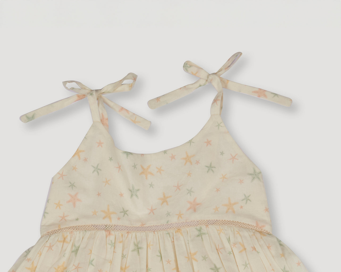 Early Sunday, Alice Dress in Star Fish print, made from Printed Cotton Cambric fabric, featuring sleeveless with adjustable tie-up straps and a tiered silhouette, shown in a closeup flat-lay view