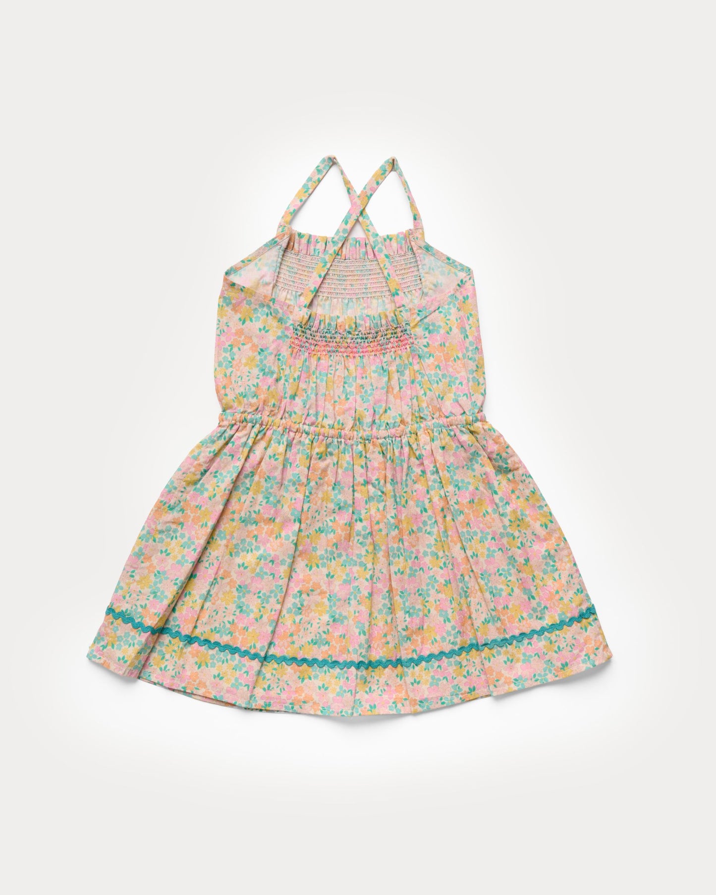 Early Sunday, Alisson Dress in Emma Floral Mint color, made from organic printed cotton cambric fabric, featuring smocked bodice, adjustable shoulder straps, sweet tassel accents, and a flowy gathered skirt, shown in a back flat-lay view.