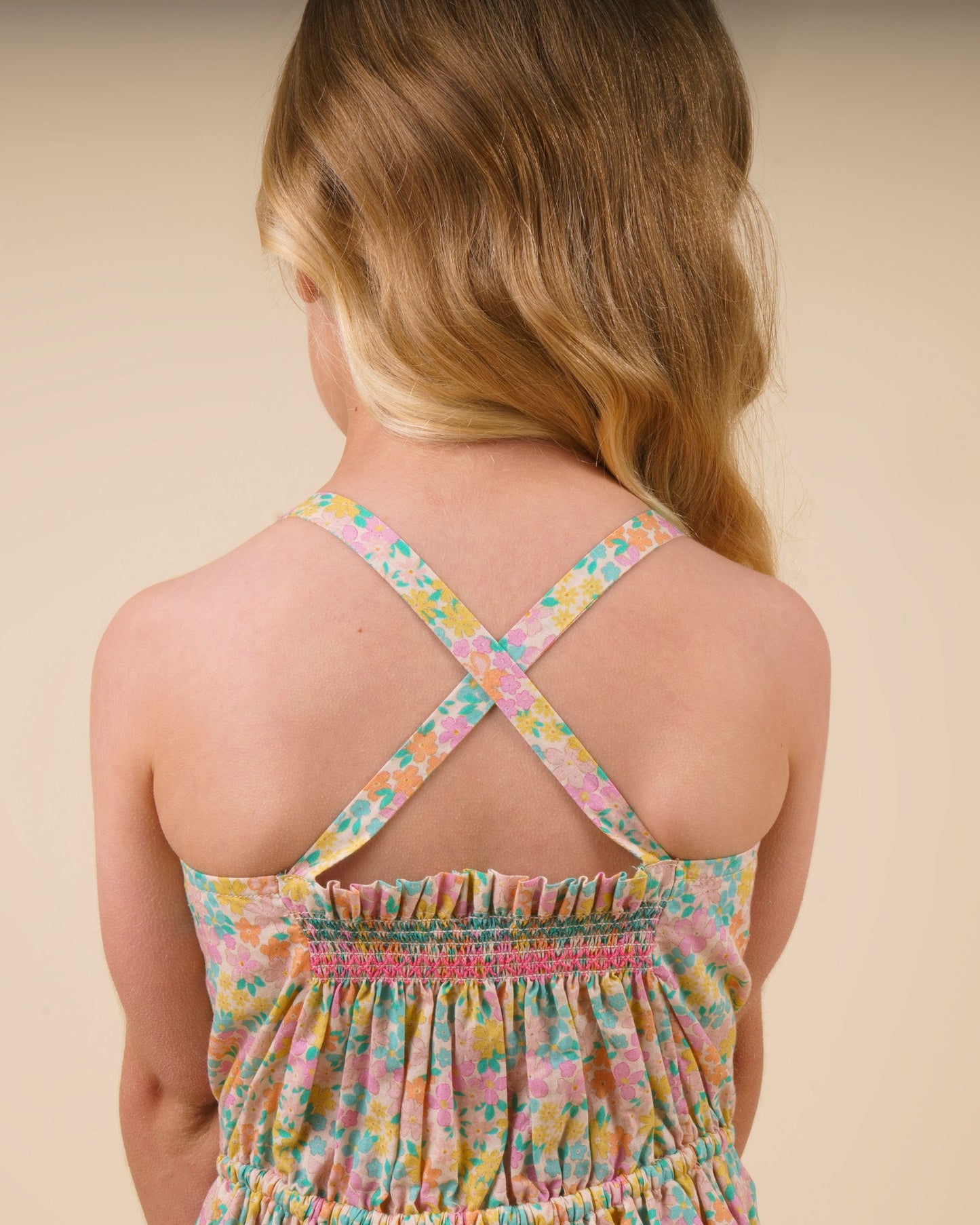 Early Sunday, Alisson Dress in Emma Floral Mint color, made from organic printed cotton cambric fabric, featuring smocked bodice, adjustable shoulder straps, sweet tassel accents, and a flowy gathered skirt, shown in a back view of model wearing.