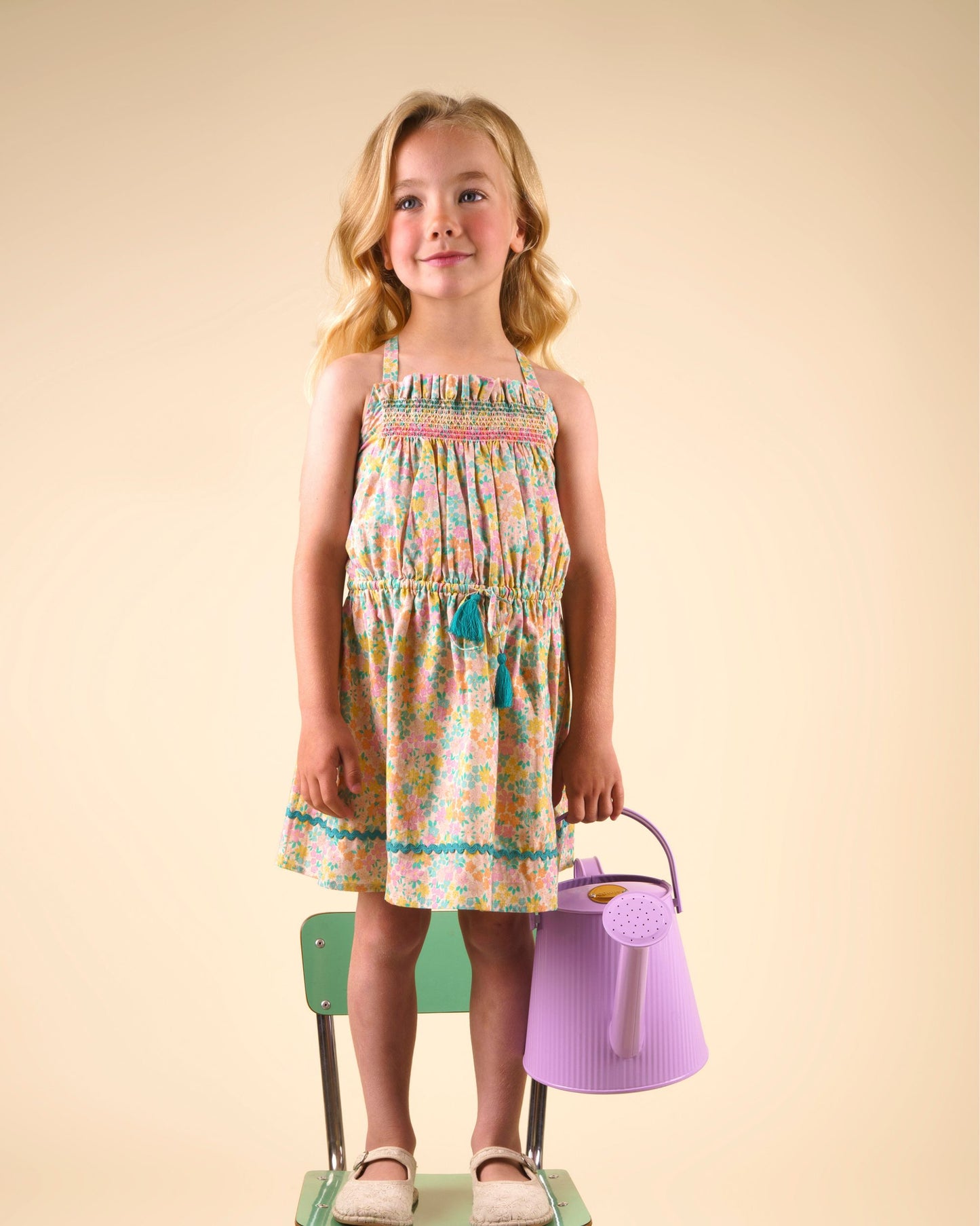 Early Sunday, Alisson Dress in Emma Floral Mint color, made from organic printed cotton cambric fabric, featuring smocked bodice, adjustable shoulder straps, sweet tassel accents, and a flowy gathered skirt, shown in a front view of model wearing.