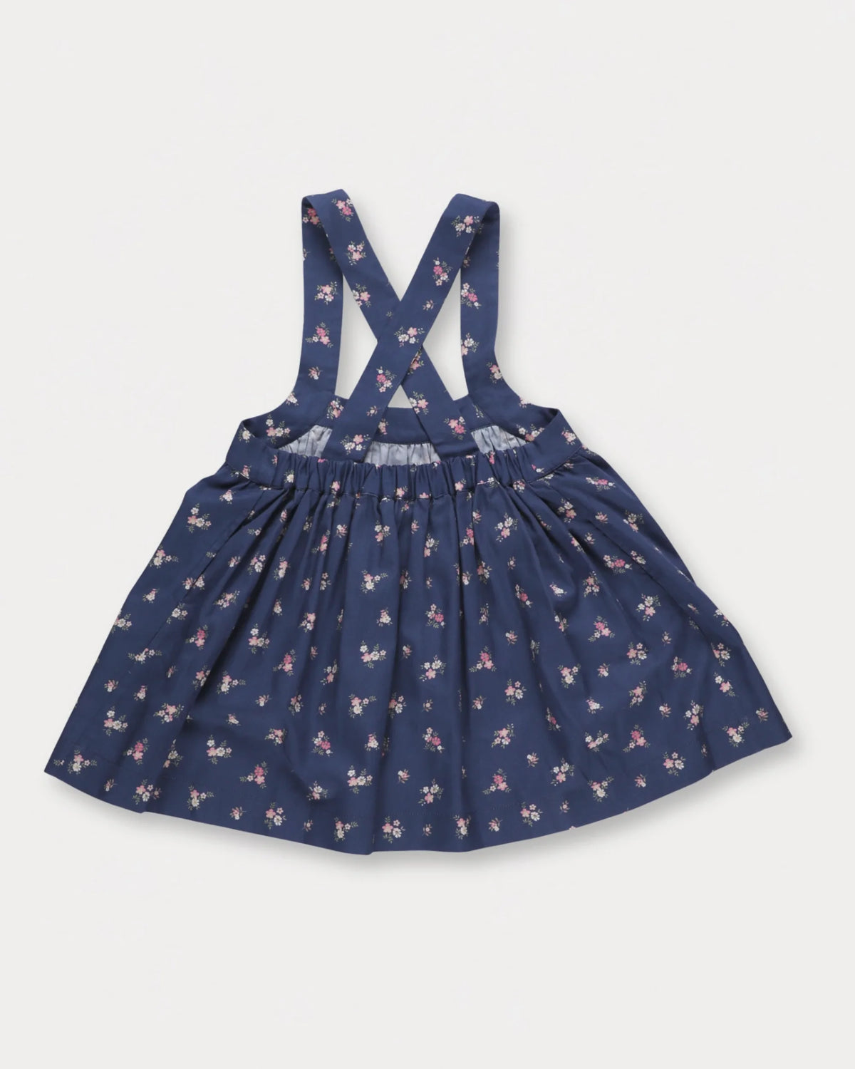 Early Sunday, Annie Skirt in Ditsy Bouquet Navy, made from Printed Cotton Satin fabric, featuring an A-line silhouette with adjustable cross-back straps and soft gathers, shown in a back flat-lay view
