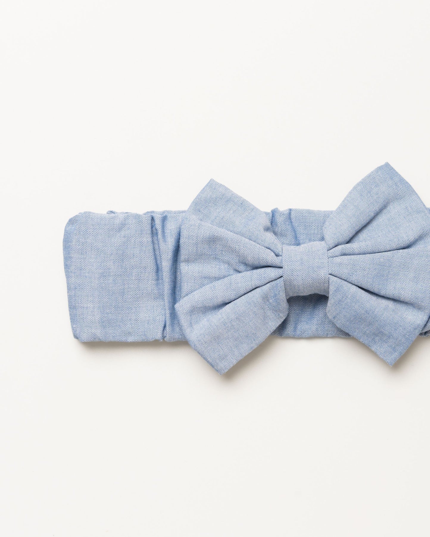 Early Sunday, Baby's Bow Headband in Summer Sky color, made from Chambray fabric, featuring a wide bow design, shown in a closeup flat-lay view