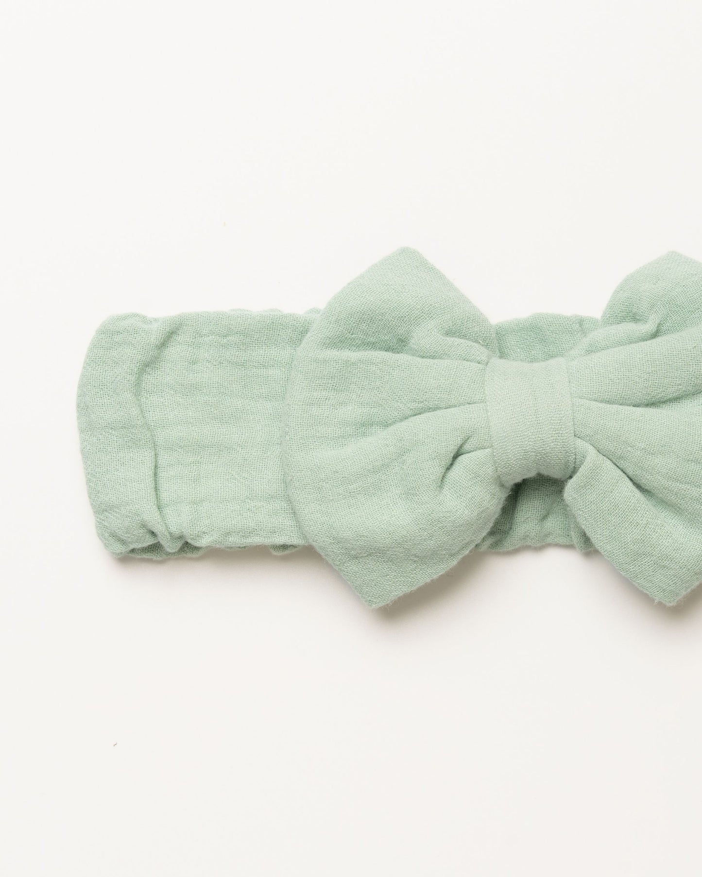Early Sunday, Baby's Bow Headband in Mint color, made from Cotton Double Gauze fabric, featuring a wide bow design, shown in a closeup flat-lay view