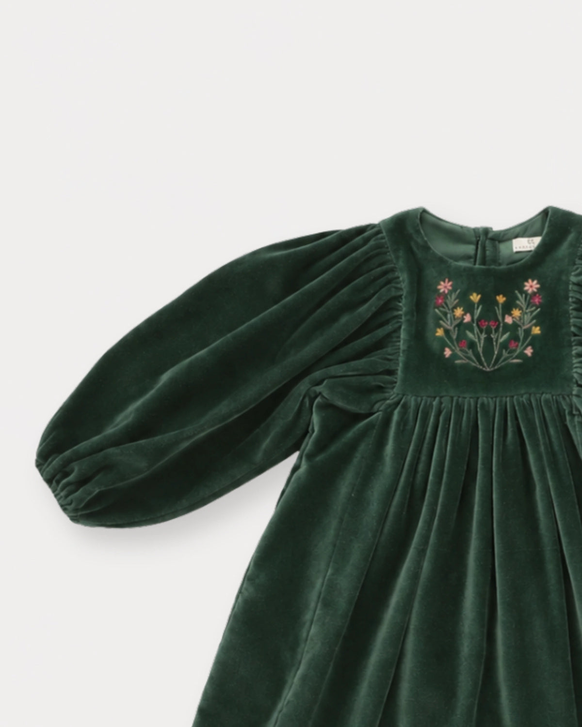 Early Sunday, Belle Dress in Forest Green, made from Cotton Velvet Velour's fabric, featuring a flowing silhouette with puff sleeves and gentle gathers, shown in a closeup flat-lay view