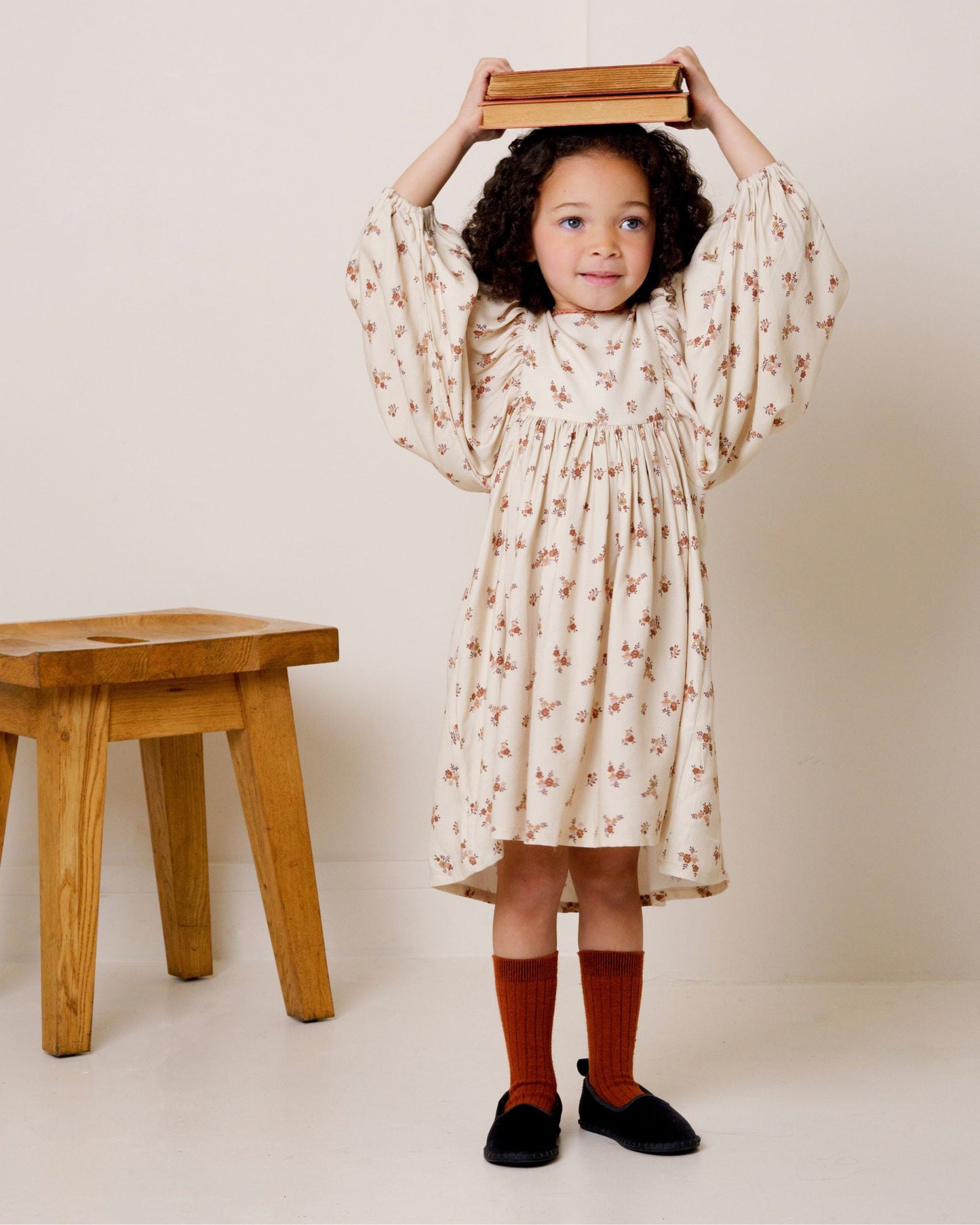 Early Sunday, Belle Dress in Ditsy Bouquet Cream print, made from Printed Viscose Rayon Twill fabric, featuring Hand-embroidered floral bodice with voluminous puff sleeves for a soft, enchanting silhouette, shown in a front view of model wearing it