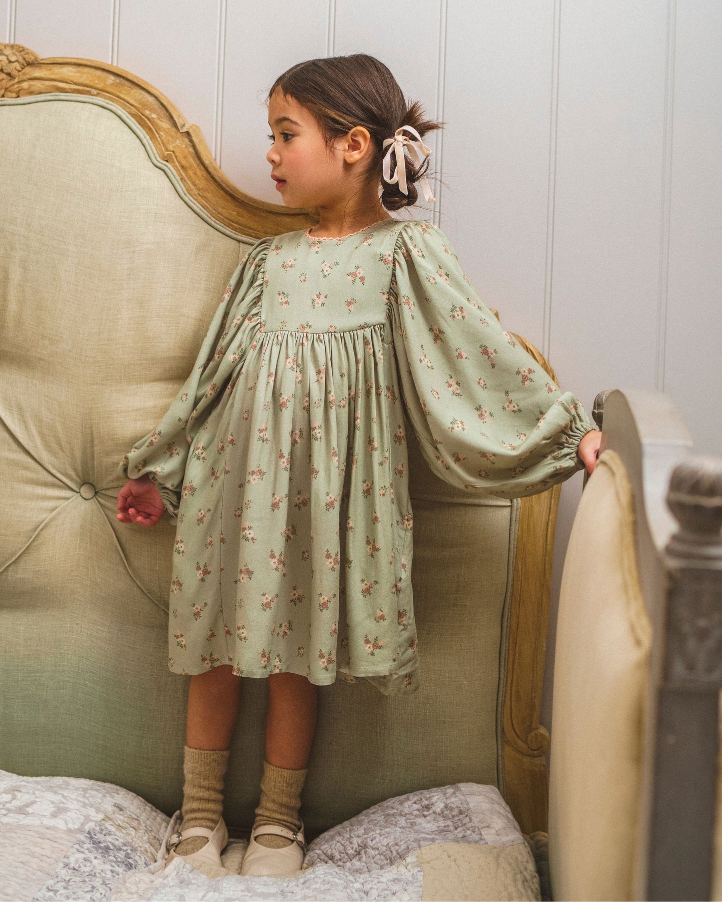 Early Sunday, Belle Dress in Ditsy Bouquet Jade print, made from Printed Viscose Rayon Twill fabric, featuring Hand-embroidered floral bodice with voluminous puff sleeves for a soft, enchanting silhouette, shown in a front view of a models wearing it in a studio setting