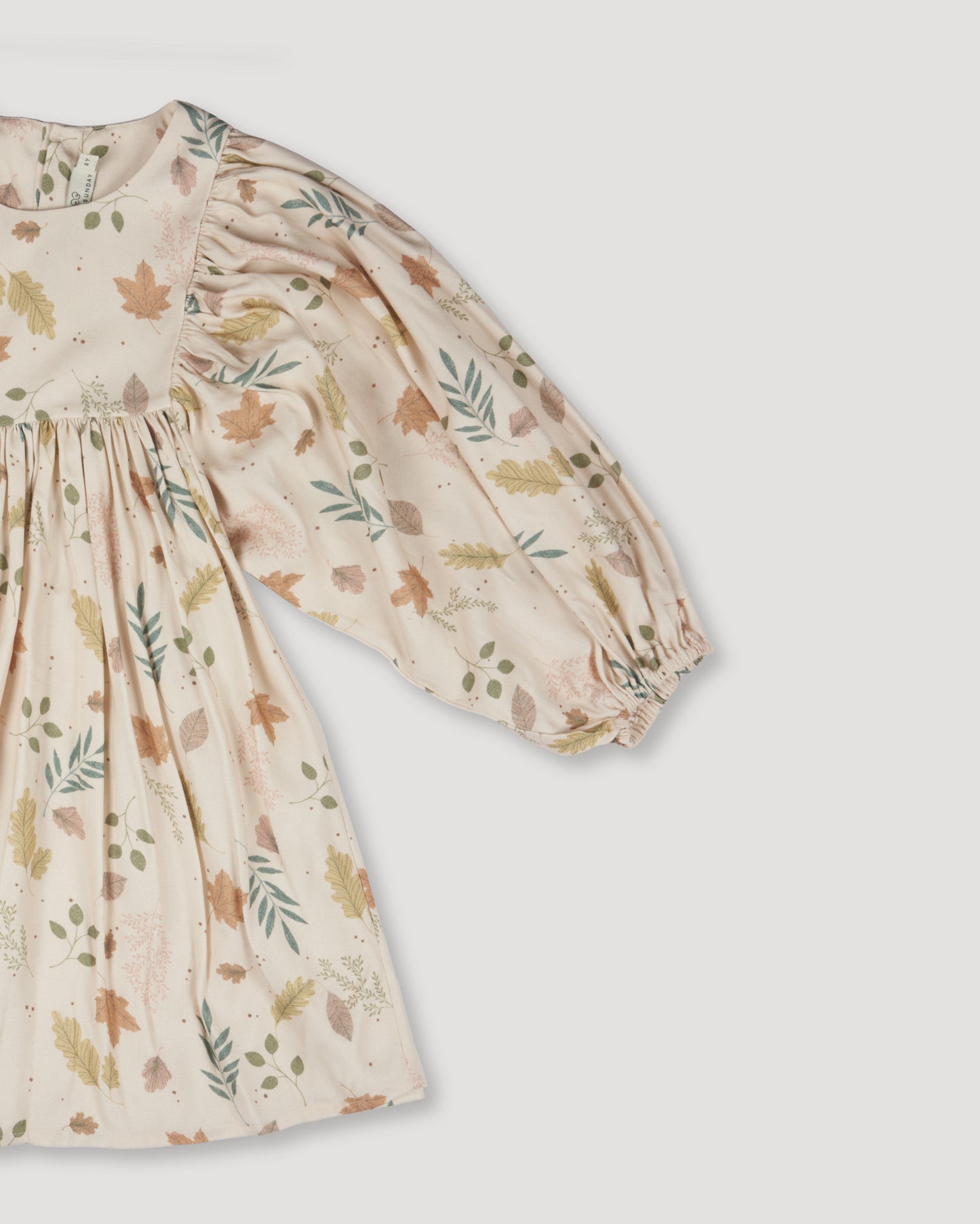 Early Sunday, Belle Dress in Falling Leaves Beige color, made from Printed Viscose Twill fabric, featuring a-line silhouette, bishop sleeves, back button closure, and mid-length, shown in a closeup flat-lay view