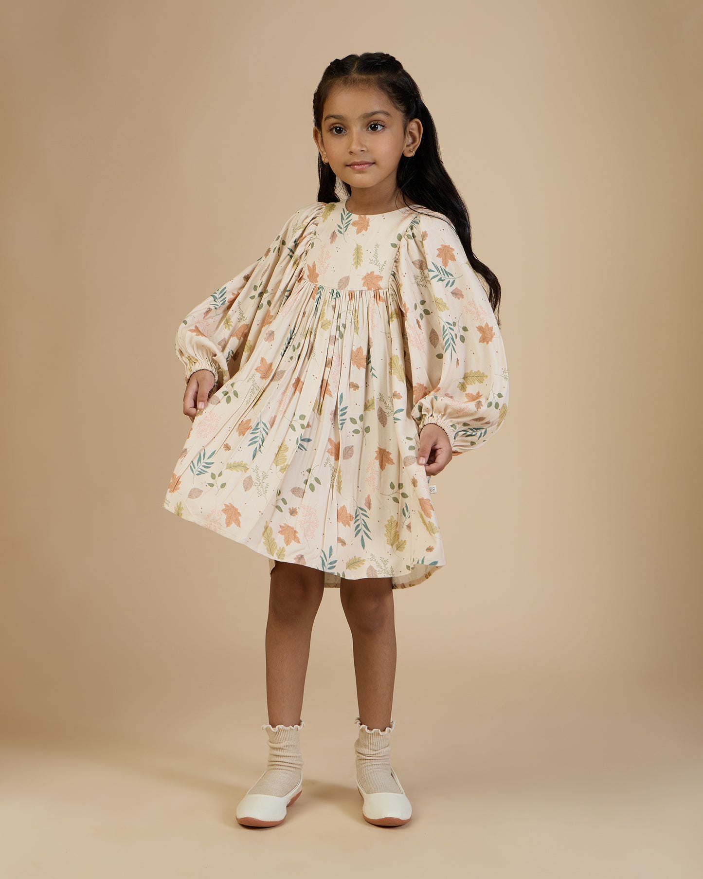 Early Sunday, Belle Dress in Falling Leaves Beige print, made from Printed Viscose Twill fabric, featuring a-line silhouette, bishop sleeves, back button closure, and mid-length, shown in a front view of model wearing it