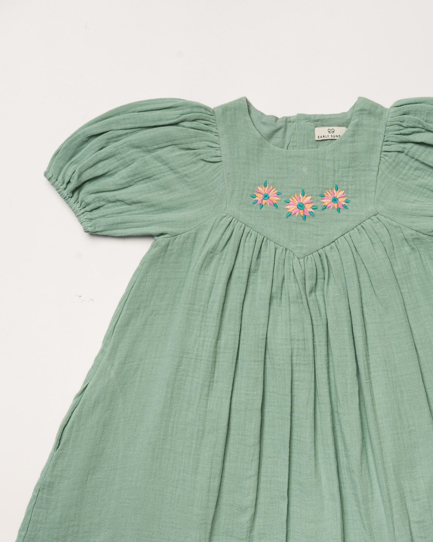 Early Sunday, Beth Dress in Mint color, made from 100% cotton double gauze solid fabric, featuring Puff sleeves, contrast scalloped collar for a vintage touch, shown in a closeup flat-lay view.