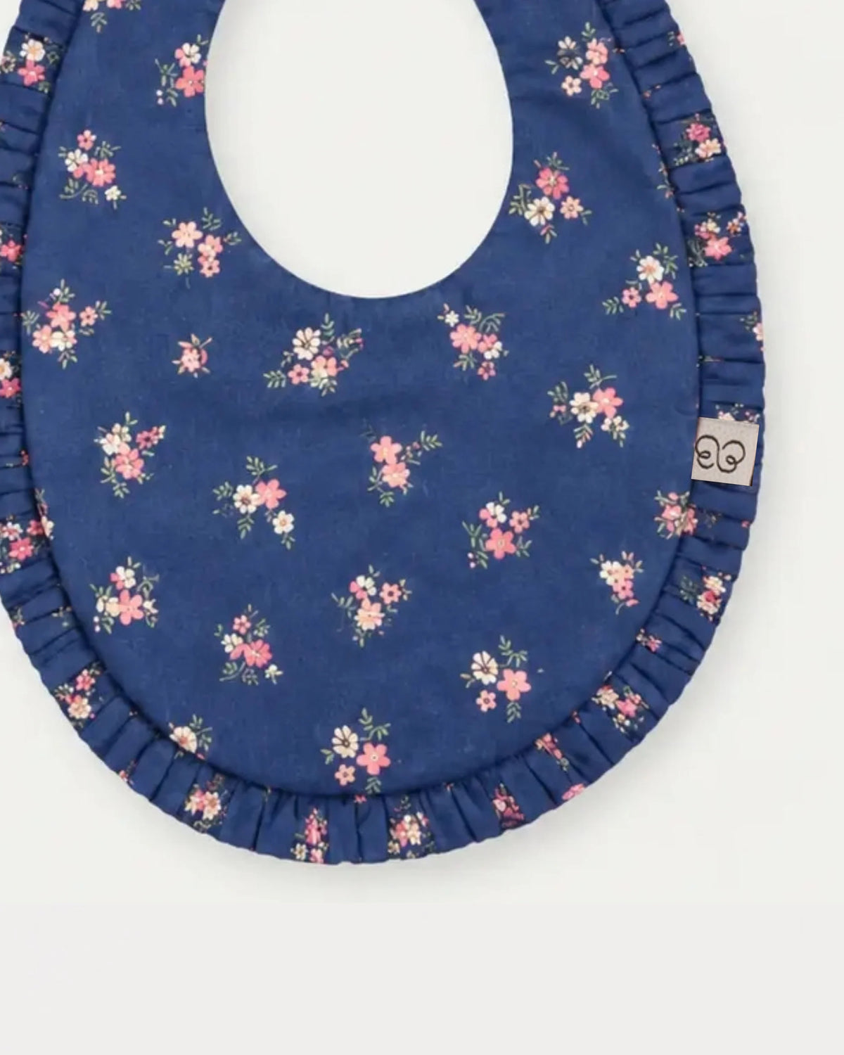 Early Sunday, Bib in Ditsy Bouquet Navy Blue, made from Printed Cotton Satin fabric, featuring featuring a soft and comfortable design with an adjustable fit, shown in a closeup flat-lay view