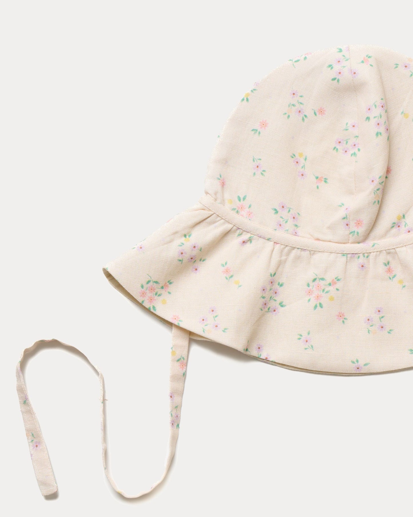 Early Sunday, Bonnie Hat Cap in Painted Bouquet print, made from 70% Cotton, 30% Linen fabric, shown in a closeup flat-lay view