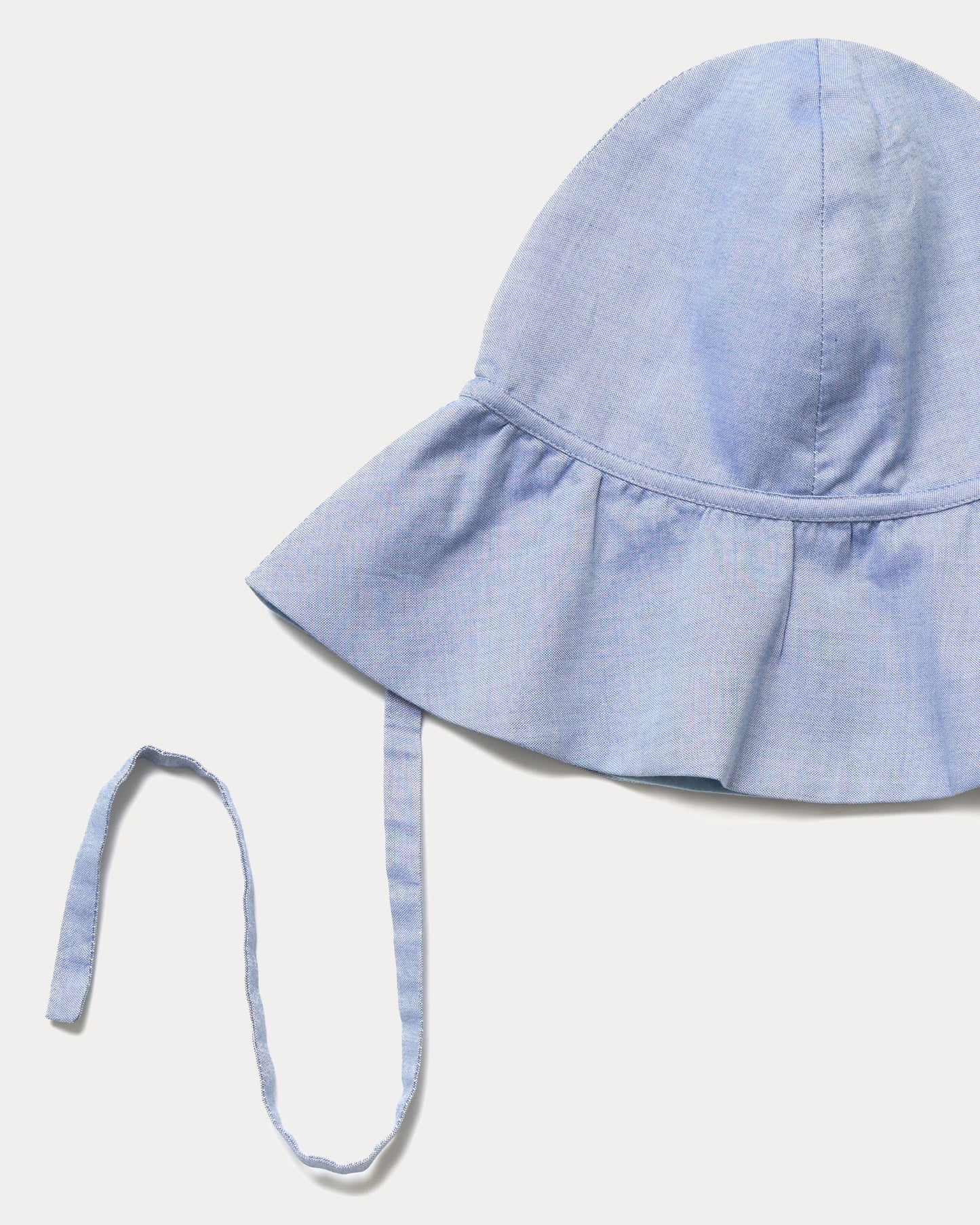Early Sunday, Bonnie Hat Cap in Summer Sky color, made from Chambray fabric, shown in a closeup flat-lay view
