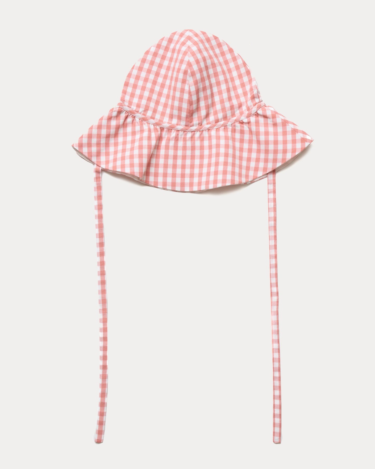 Early Sunday, Bonnie Hat Cap in Peony color, made from Gingham Check fabric, shown in a front flat-lay view with wide brim and tie straps
