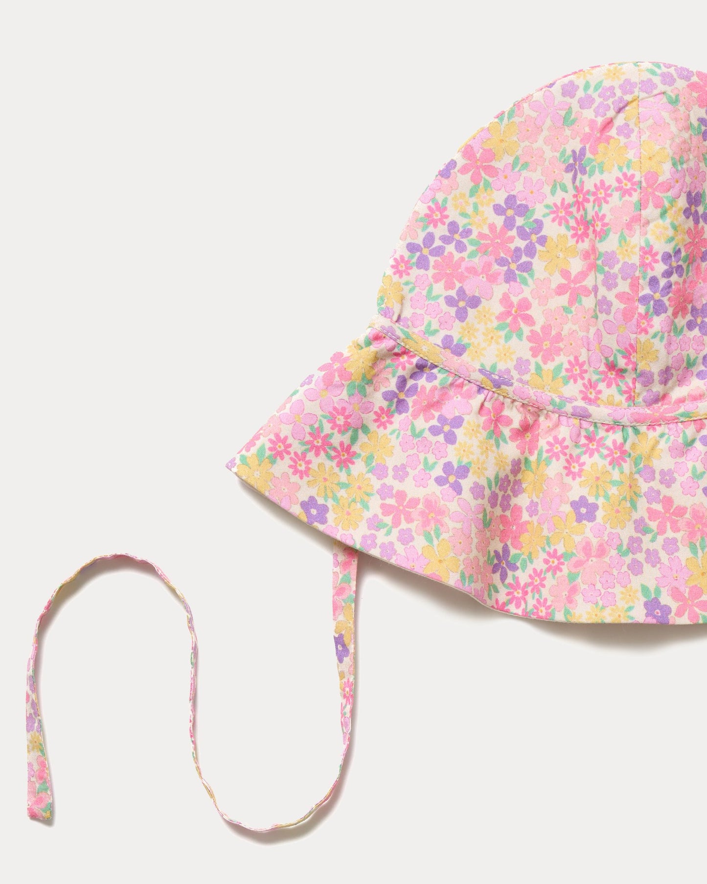 Early Sunday, Bonnie Hat Cap in Emma Floral Purple color, made from Organic Printed Cotton Cambric fabric, shown in a closeup flat-lay view