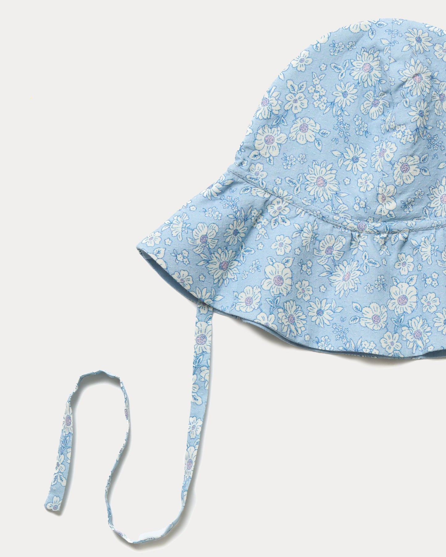 Early Sunday, Bonnie Hat Cap in Tonal Floral Blue color, made from Printed Tiny Swiss Dobby fabric, shown in a closeup flat-lay view