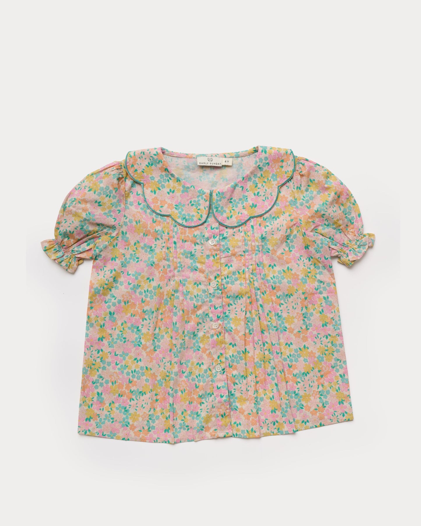 Early Sunday, Camelia Blouse in Emma Floral Mint color, made from printed 60s cotton cambric fabric, featuring short sleeves with peter pan collar, shown in a front flat-lay view