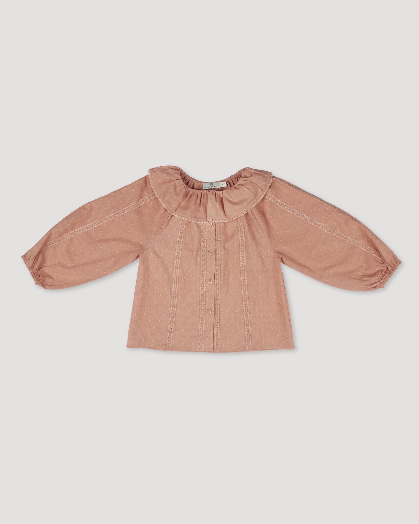 Early Sunday, Cecilia Blouse in Earthy Pink color, made from Cotton Swiss Dobby fabric, featuring relaxed fit, frill neckline, long sleeves with elasticated cuffs, and MOP buttons, shown in a front flat-lay view