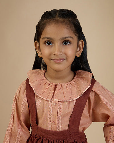 Early Sunday, Cecilia Blouse in Earthy Pink print, made from Cotton Swiss Dobby fabric, featuring relaxed fit, frill neckline, long sleeves with elasticated cuffs, and MOP buttons, shown in a close up shot of model wearing it