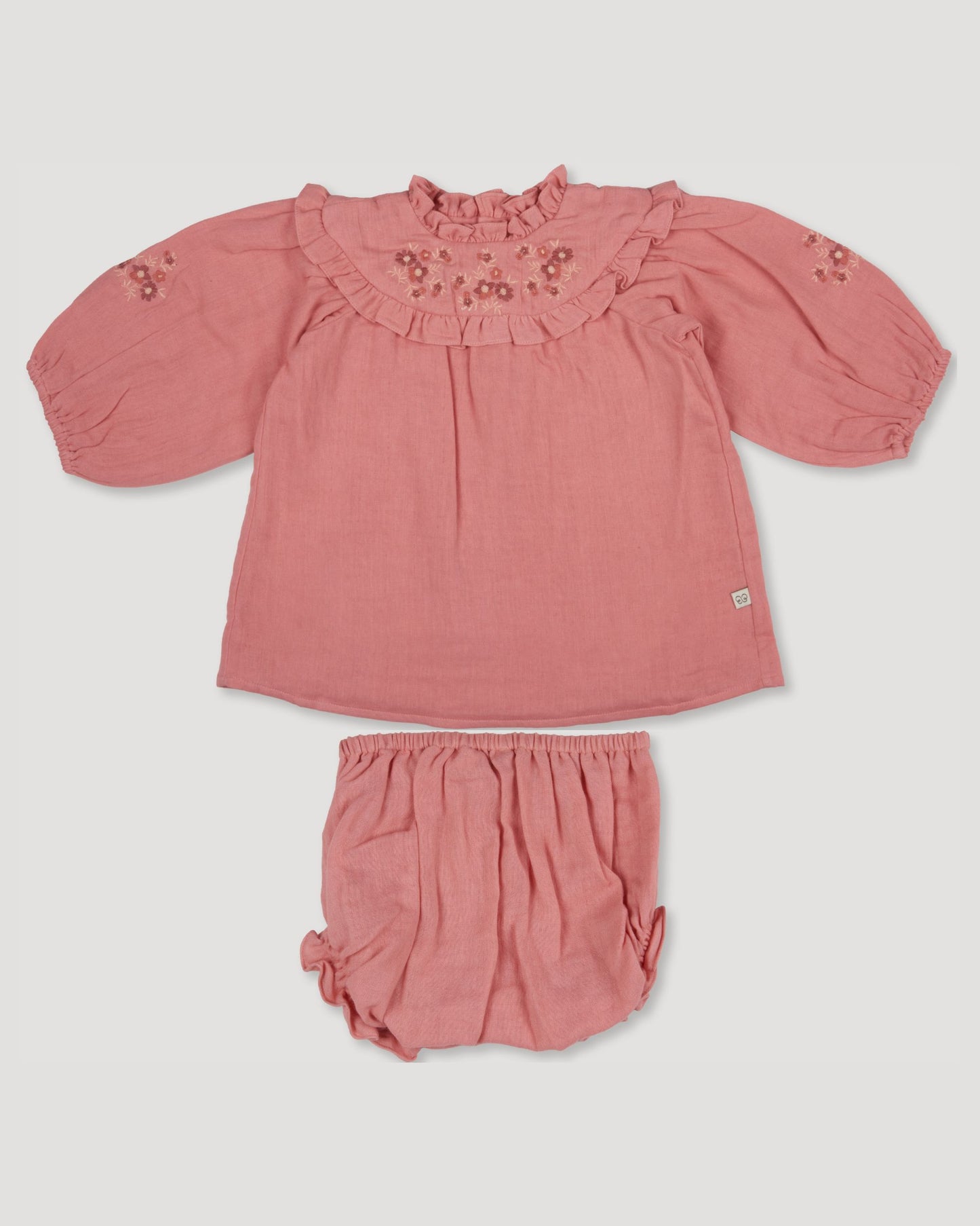 Early Sunday, Charlie Baby Dress & Bloomer Set in Rose color, made from Dyed Cotton Double Gauze fabric, featuring ruffled neckline with floral embroidery & matching bloomers, shown in a front flat-lay view