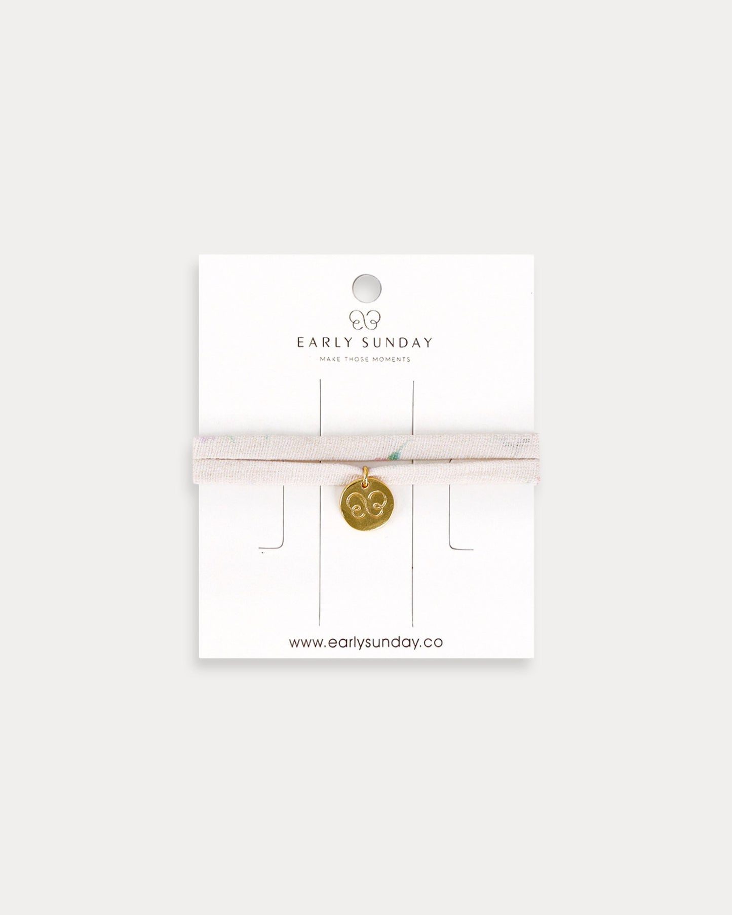 Early Sunday, Charm Bracelet in Painted Bouquet print, made from Printed 70% Cotton, 30% Linen fabric, featuring a soft fabric bracelet design with a charm, shown in a front flat-lay view