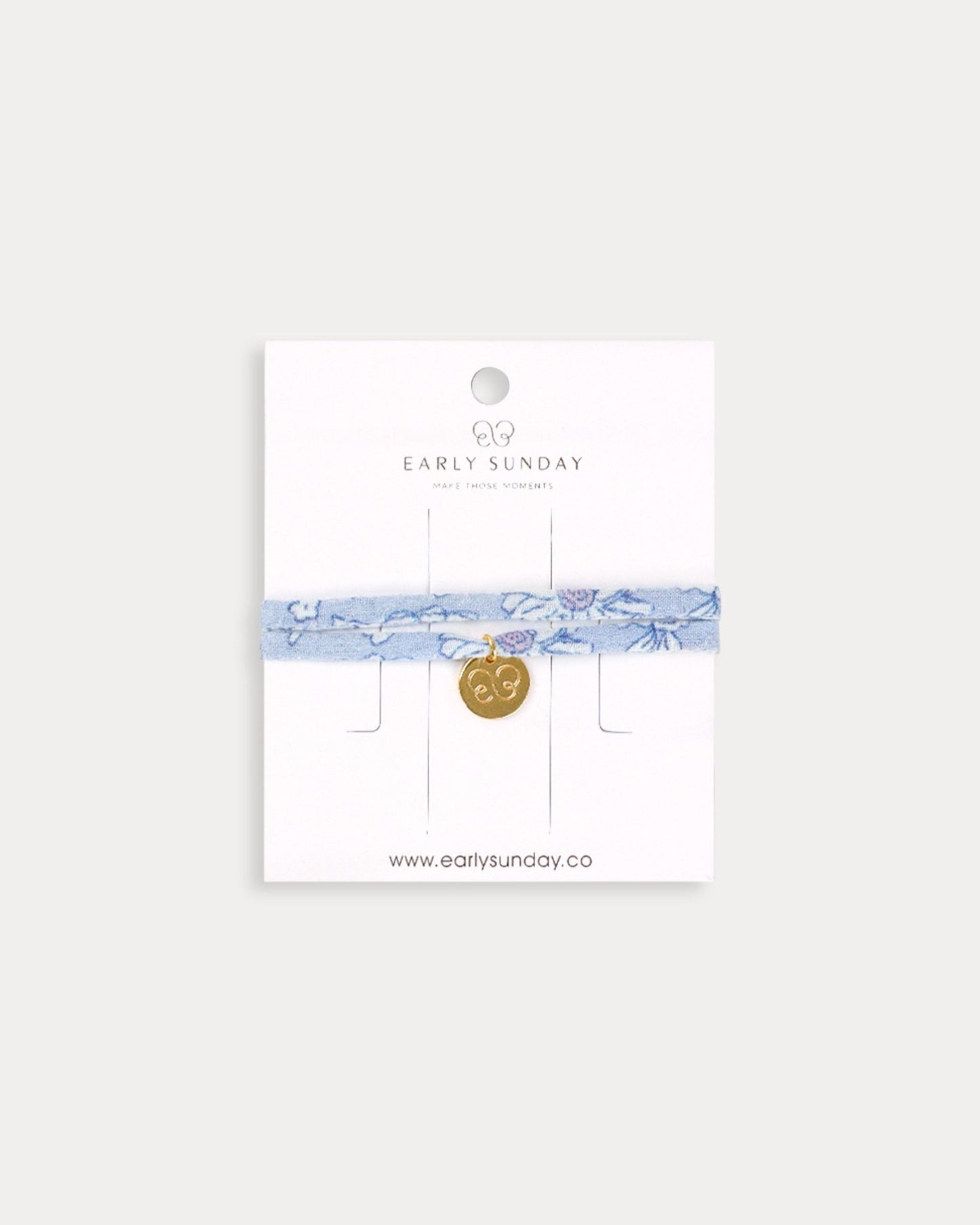 Early Sunday, Charm Bracelet in Tonal Floral Blue color, made from Printed Cotton Tiny Swiss Dobby fabric, featuring a soft fabric bracelet design with a charm, shown in a front flat-lay view