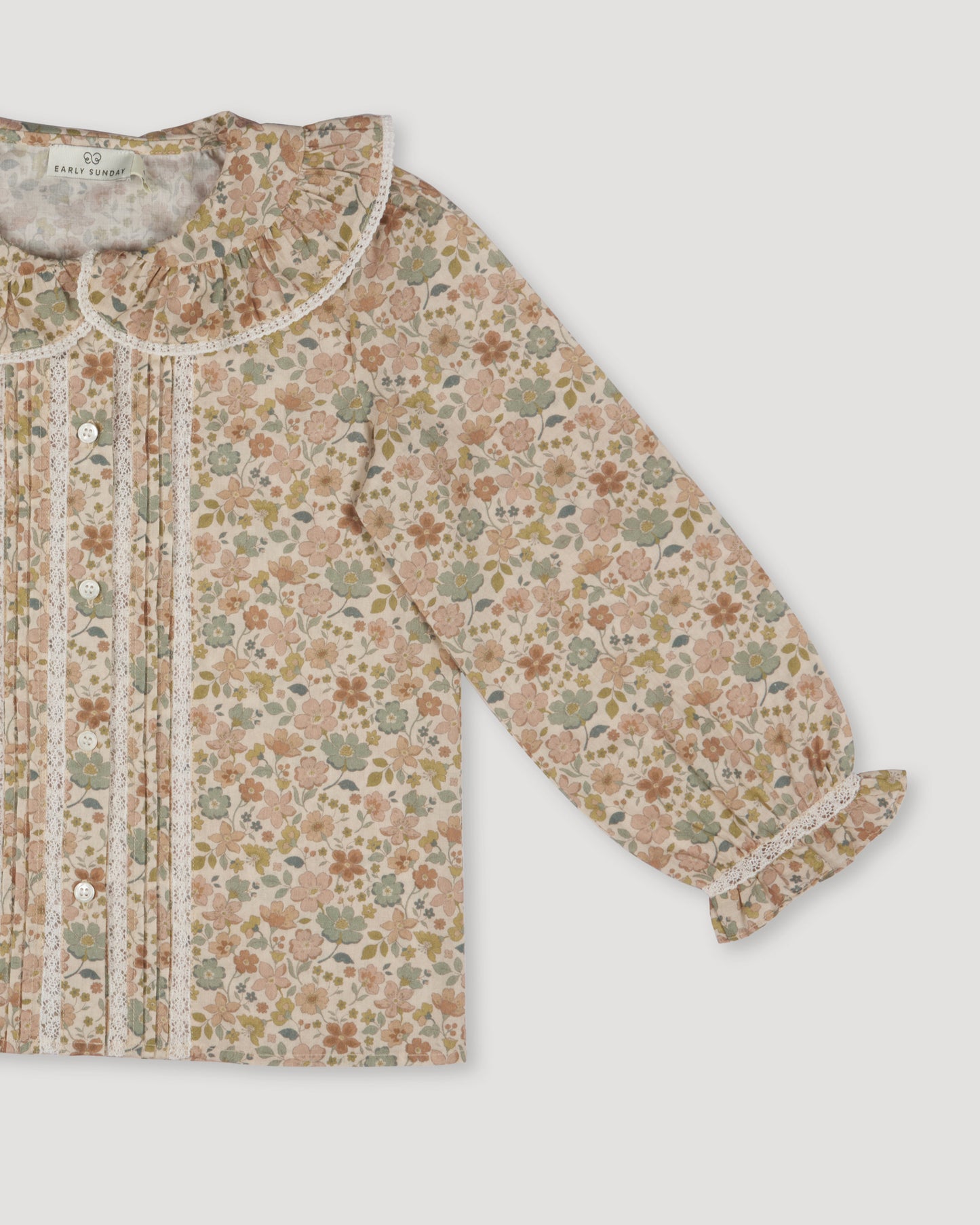 Early Sunday, Ella Blouse in Garden Flowers Cream, made from Printed Cotton Cambric fabric, featuring relaxed fit, frill detailing on the collar, and lace inserts, shown in a closeup flat-lay view