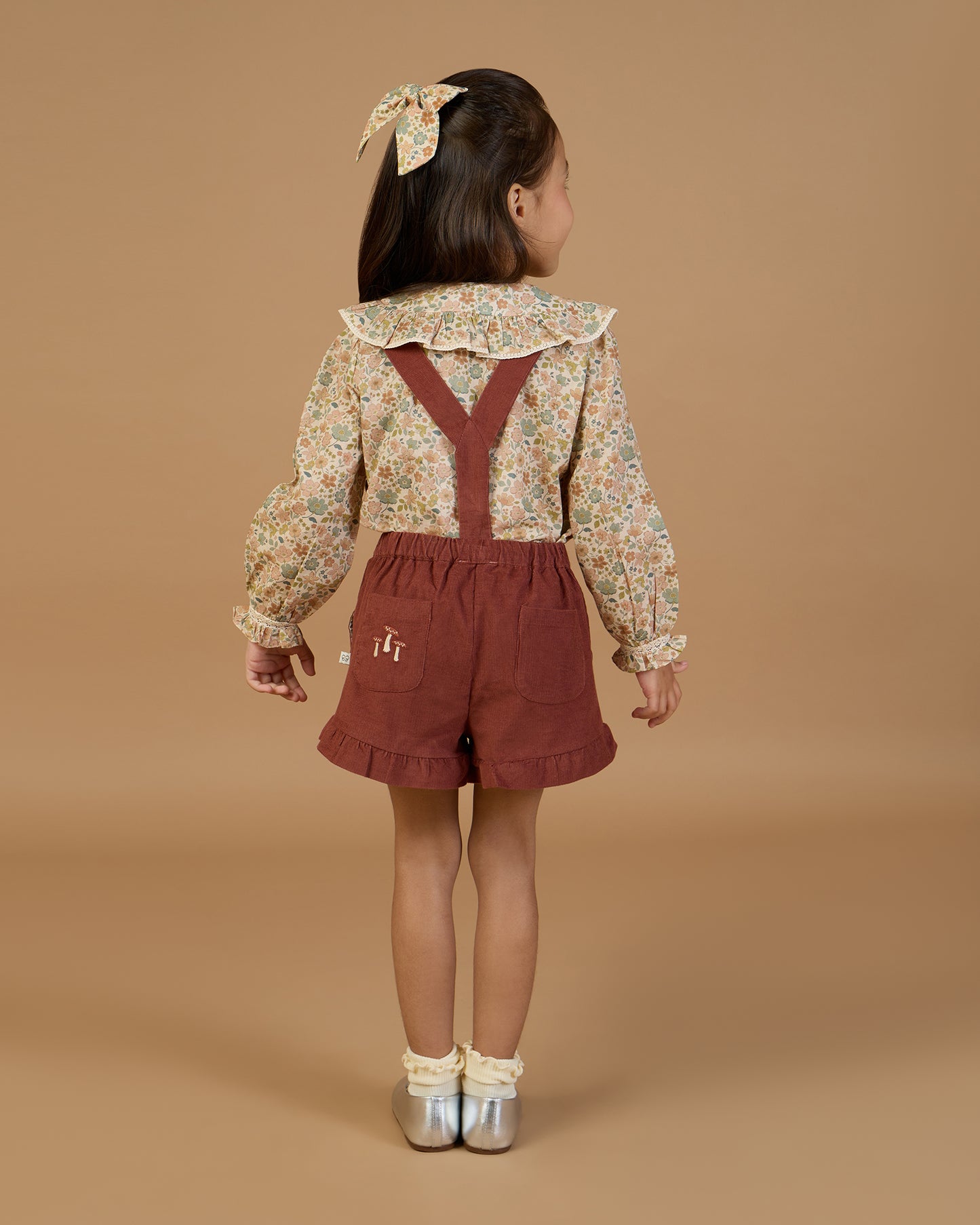 Early Sunday, Ella Blouse in Garden Flowers Cream, made from Printed Cotton Cambric fabric, featuring relaxed fit, frill detailing on the collar, and lace inserts, shown in a back view of model wearing it