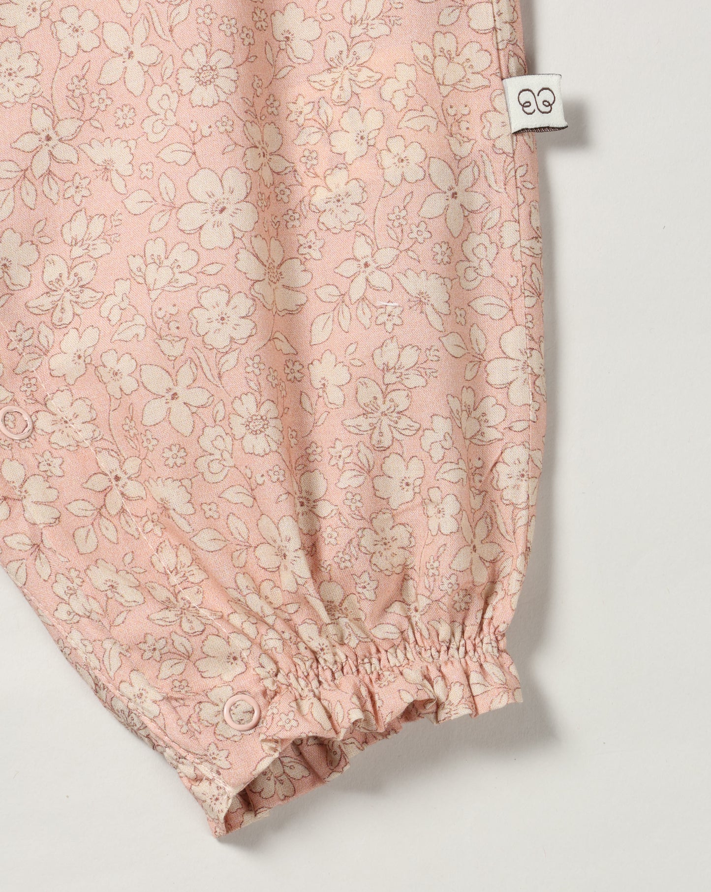 Early Sunday, Emma Baby Smocked Overalls Romper in Garden Flowers print, made from Printed Cotton Cambric fabric, featuring a relaxed fit with smocked chest band & frilled sleeves, shown in a closeup flat-lay view