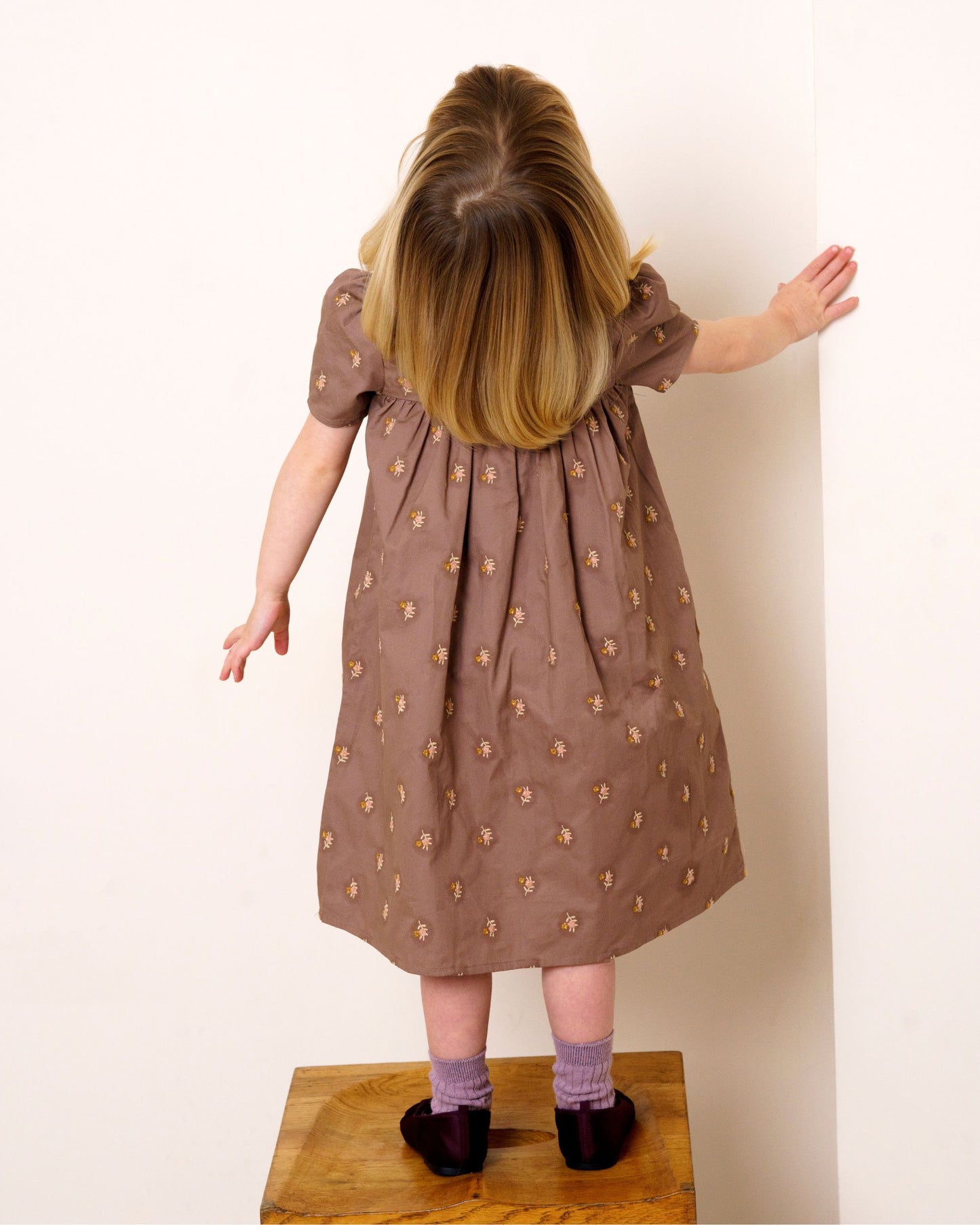 Early Sunday, Erika Dress in Bark, made from All-Over Embroidered 30s Cotton Brushed Twill fabric, featuring Flowy A-line silhouette allows ease of movement and day-long comfort, shown in a back view of model wearing it