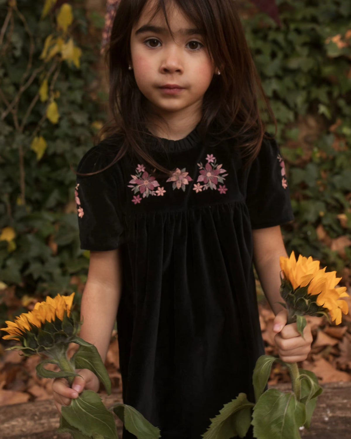 Early Sunday, Erika Dress in Black, made from Cotton Velvet Velour's fabric, featuring a beautiful embroidery with frilled neckline, shown in a close up shot of model wearing it