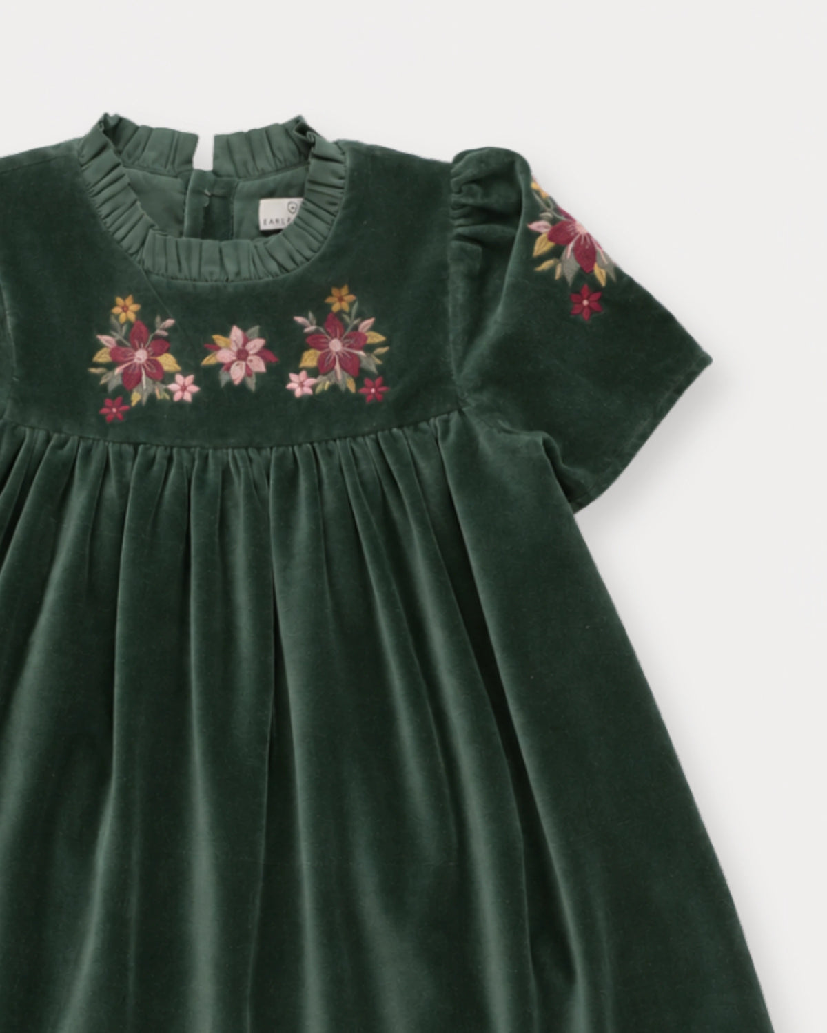 Early Sunday, Erika Dress in Forest Green, made from Cotton Velvet Velour's fabric, featuring a beautiful embroidery with frilled neckline, shown in a closeup flat-lay view