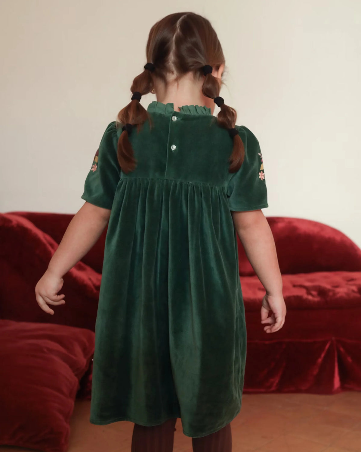 Early Sunday, Erika Dress in Forest Green, made from Cotton Velvet Velour's fabric, featuring a beautiful embroidery with frilled neckline, shown in a back view of model wearing it