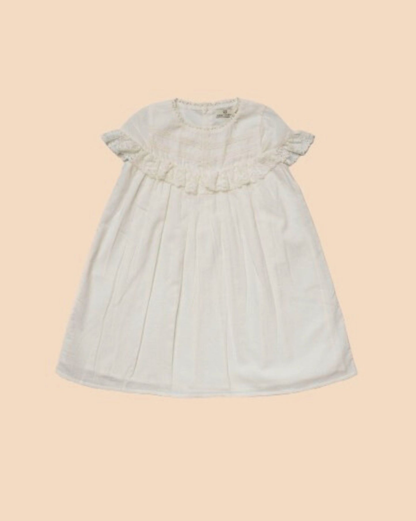 Early Sunday, Faustine Dress in Ivory color, made from 100% cotton swiss dobby tiny dots fabric, featuring Soft gathers with delicate ruffle accents, shown in a front flat-lay view