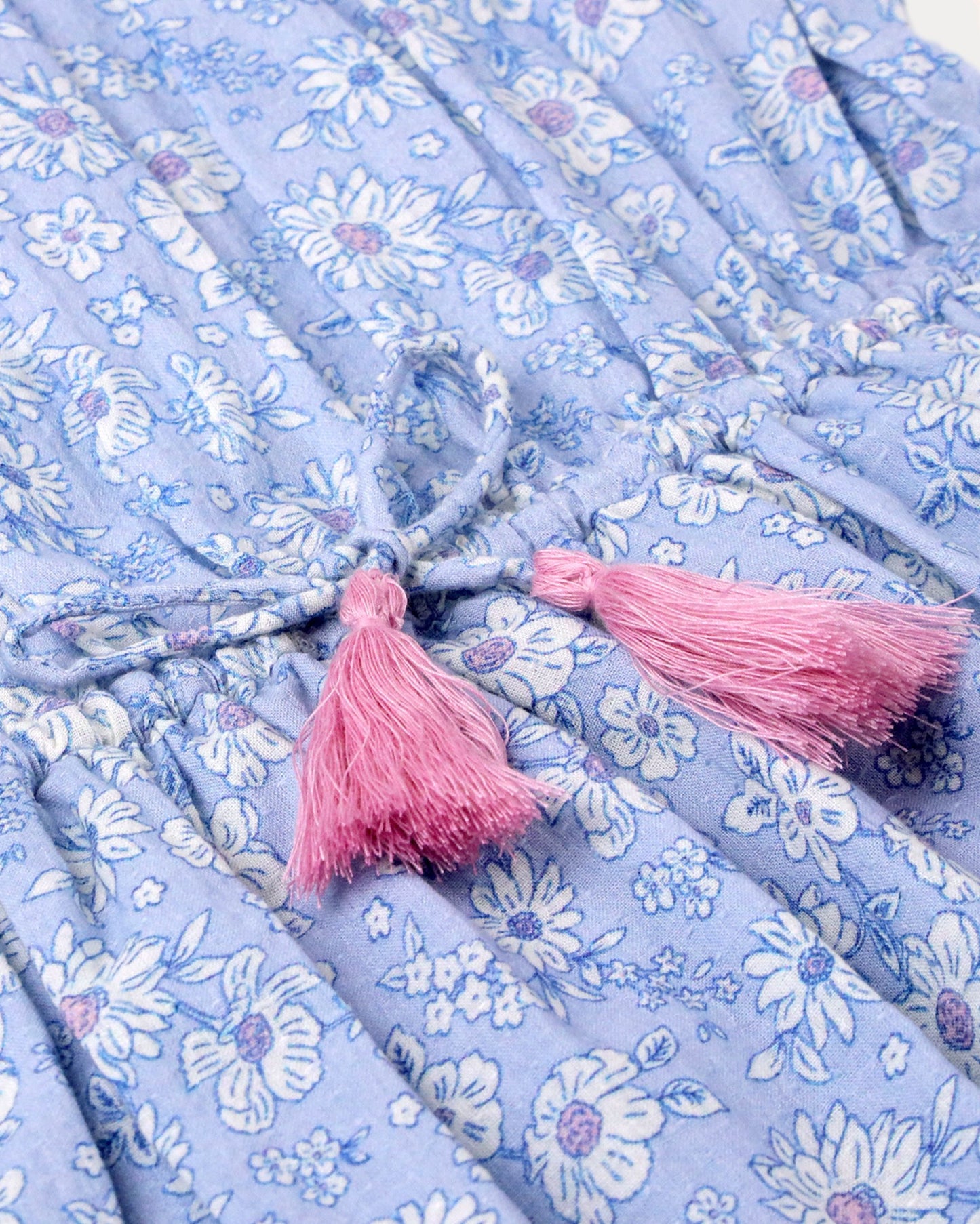 Early Sunday, Florence Dress in Tonal Floral Blue color, made from printed cotton tiny swiss dobby fabric, featuring Ruffle detailing on the yoke and sleeves, lace accents, gathered waist with tassel tie, shown in a closeup flat-lay view
