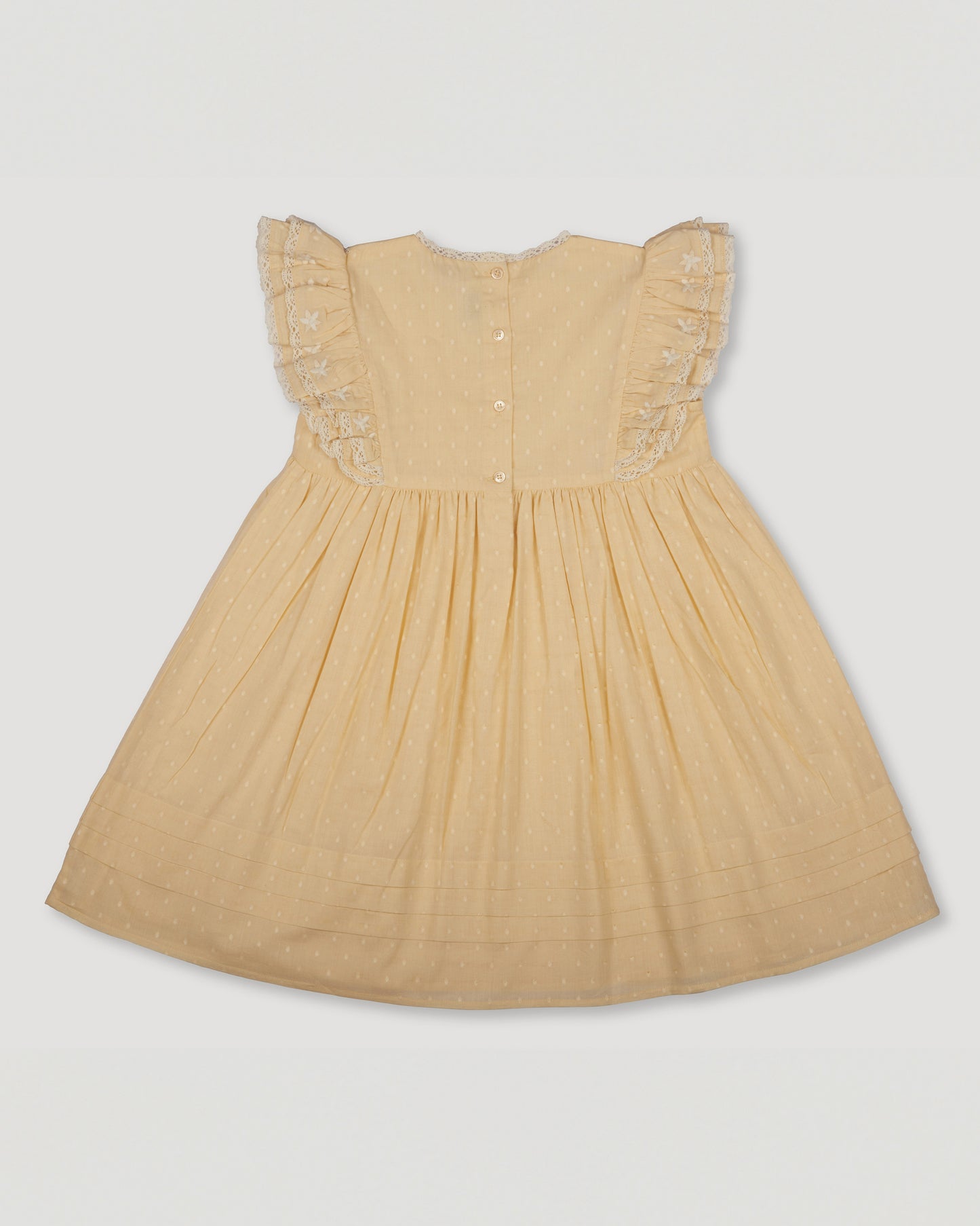 Early Sunday, Georgia Dress in Vanilla color, made from Cotton Dobby Swiss Dots fabric, featuring Flutter sleeves, pintuck detailing, and a flowy, gathered silhouette, shown in a back flat-lay view