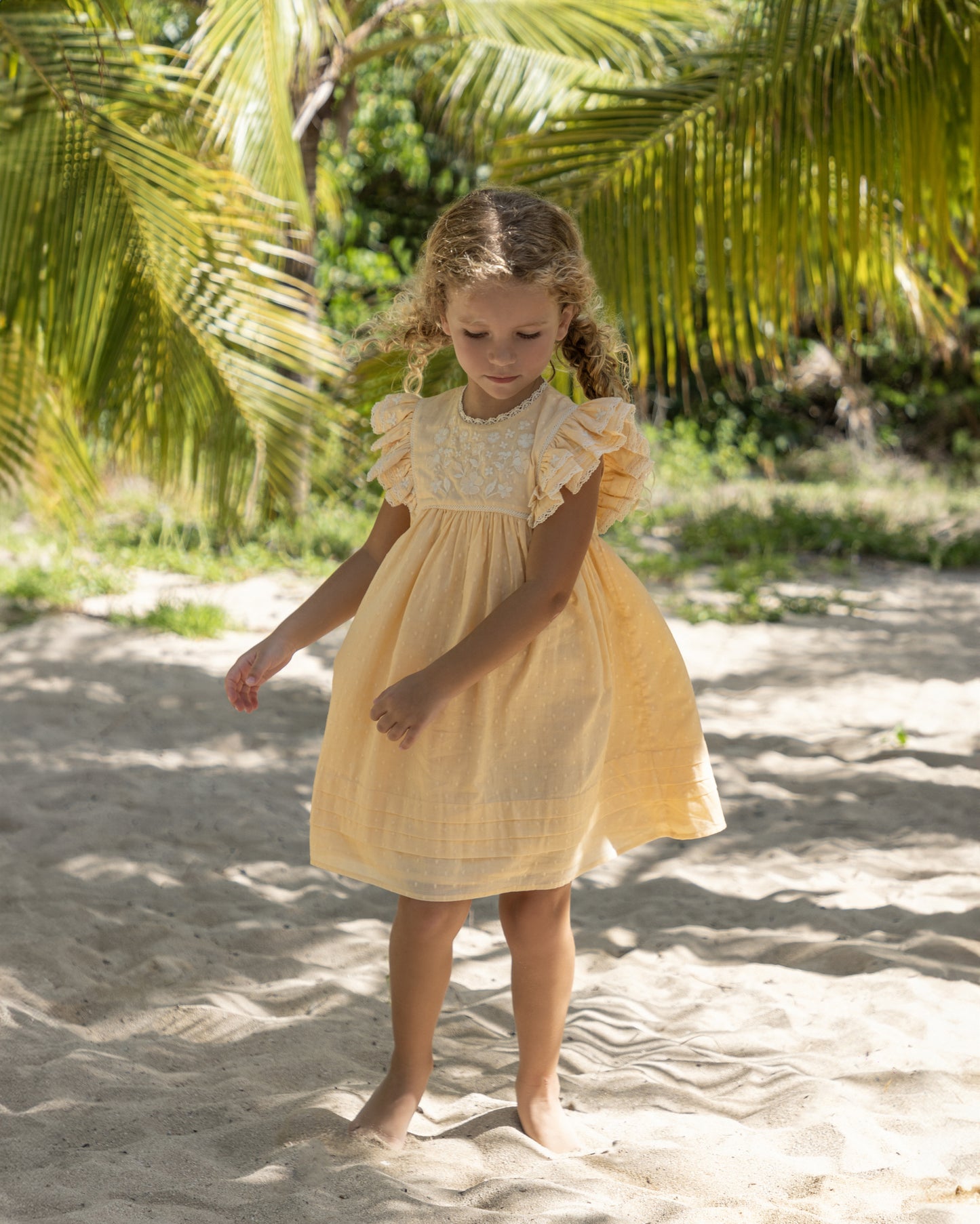Early Sunday, Georgia Dress in Vanilla color, made from Cotton Dobby Swiss Dots fabric, featuring flutter sleeves, pintuck detailing, and a flowy, gathered silhouette, shown in a front view of model wearing it