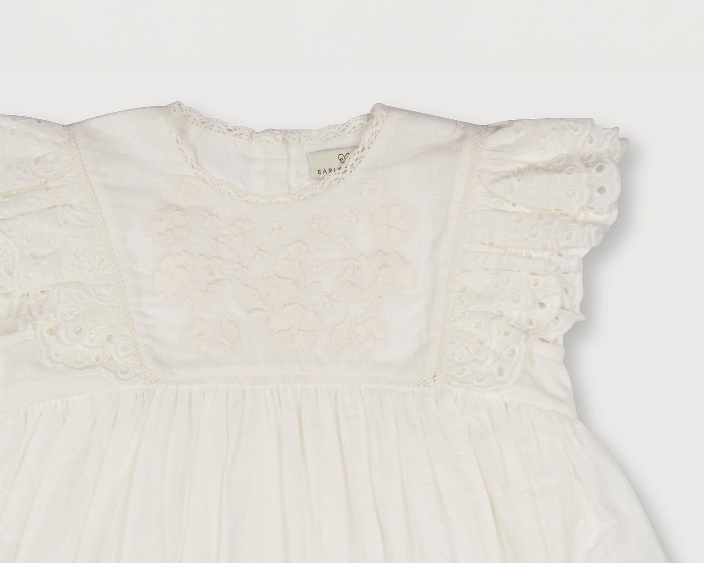 Early Sunday, Georgia Dress in Ivory print, made from Cotton Tiny Swiss Dots fabric, featuring Flutter sleeves, pintuck detailing, and a flowy, gathered silhouette, shown in a closeup flat-lay view