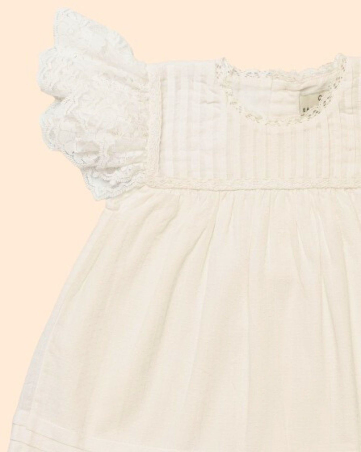 Early Sunday, Grace Baby Dress & Bloomer Set in Ivory color, made from 100% Cotton Swiss Dobby fabric, featuring a sleeveless design with wide shoulder straps & matching bloomers, shown in a closeup flat-lay view