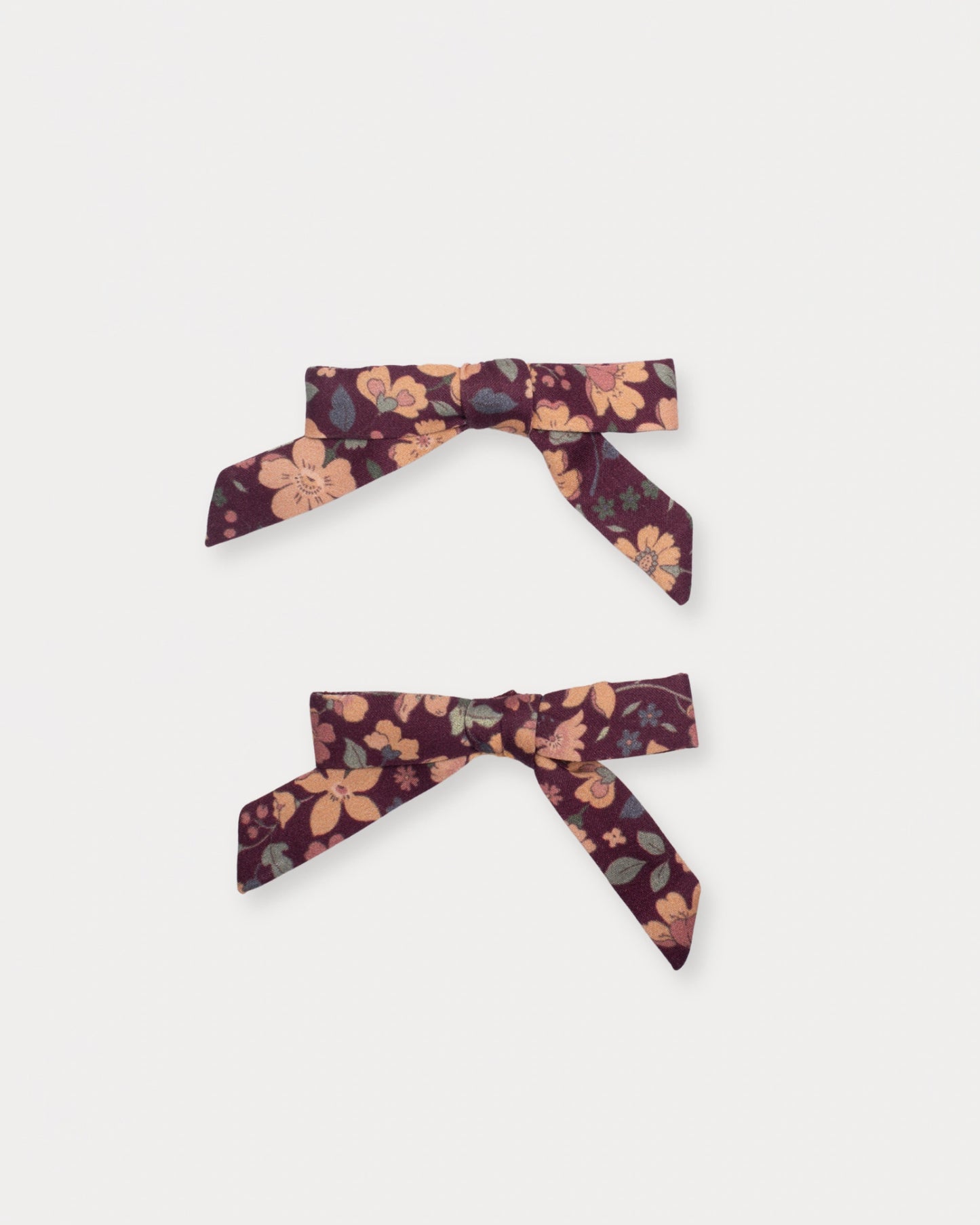 Early Sunday, Grace Clip in Garden Flowers Plum, made from Printed Cotton Satin fabric, featuring a set of two bow clips with a secure fit, shown in a front flat-lay view