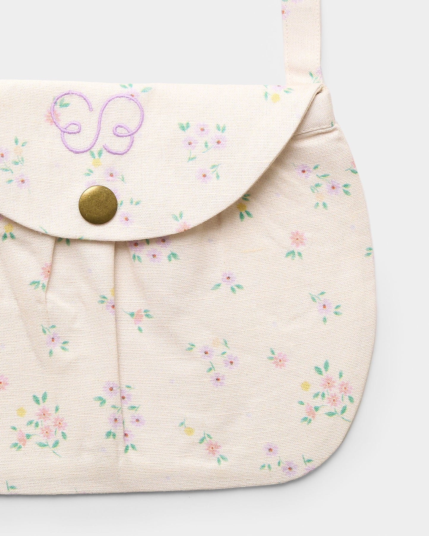 Early Sunday, Hudson Purse in Painted Bouquet print, made from 70% Cotton, 30% Linen fabric, featuring a gathered sling purse design with a flap closure, shown in a closeup flat-lay view