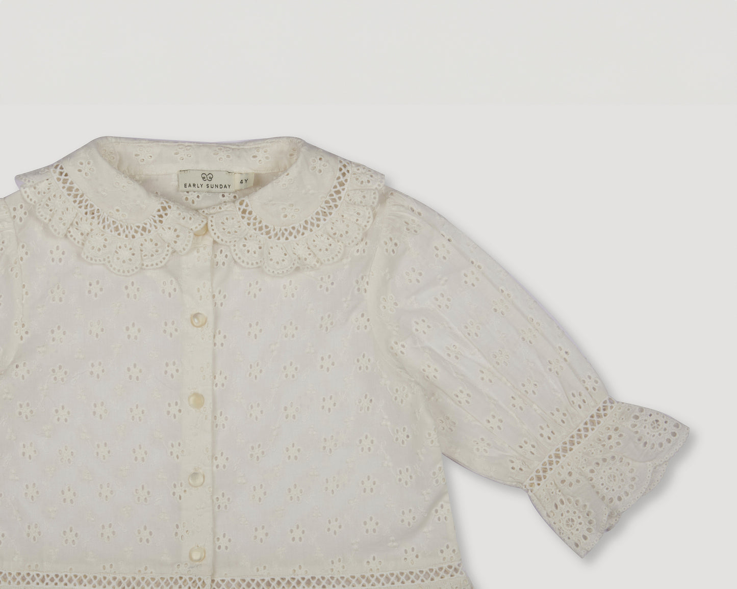 Early Sunday, Iris Blouse in Ivory color, made from All-Over Eyelet Embroidered Cotton Schifflie fabric, featuring relaxed fit with delicate detailing for a timeless and feminine look, shown in a closeup flat-lay view