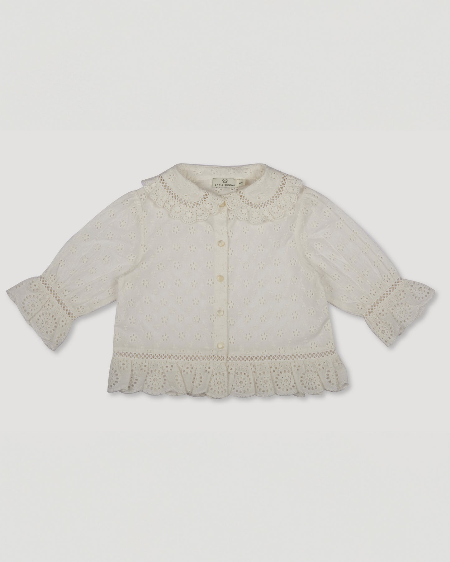 Early Sunday, Iris Blouse in Ivory color, made from All-Over Eyelet Embroidered Cotton Schifflie fabric, featuring relaxed fit with delicate detailing for a timeless and feminine look, shown in a front flat-lay view