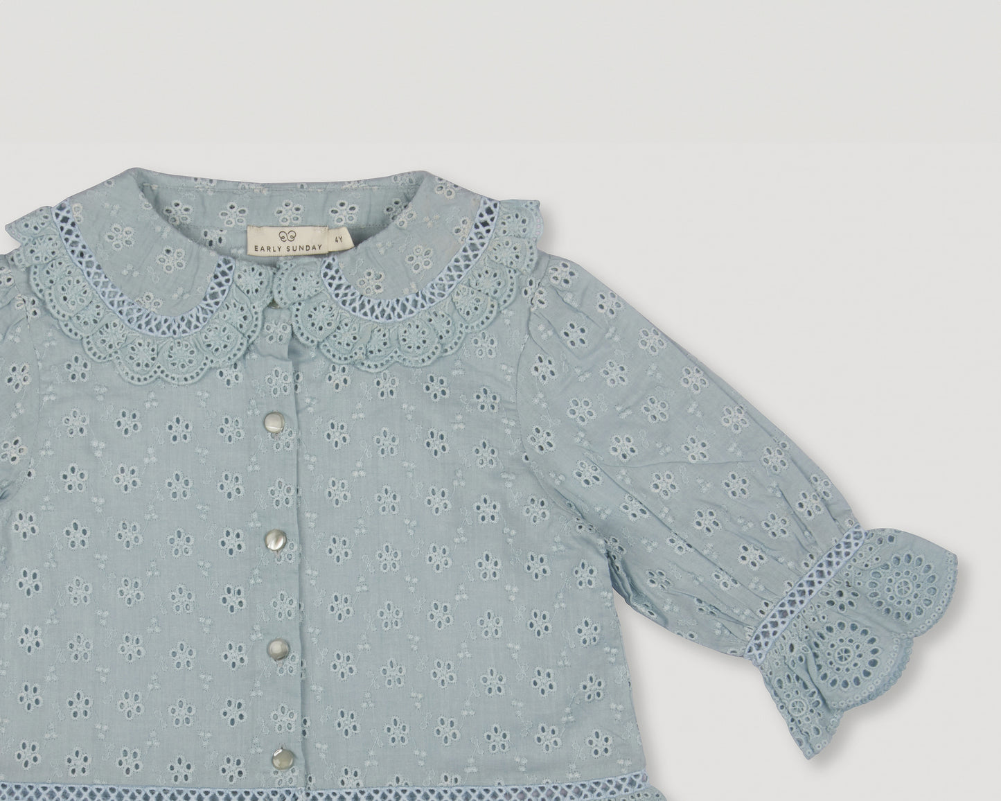 Early Sunday, Iris Blouse in Sea Dream color, made from All-Over Eyelet Embroidered Cotton Schifflie fabric, featuring relaxed fit with delicate detailing for a timeless and feminine look, shown in a closeup flat-lay view