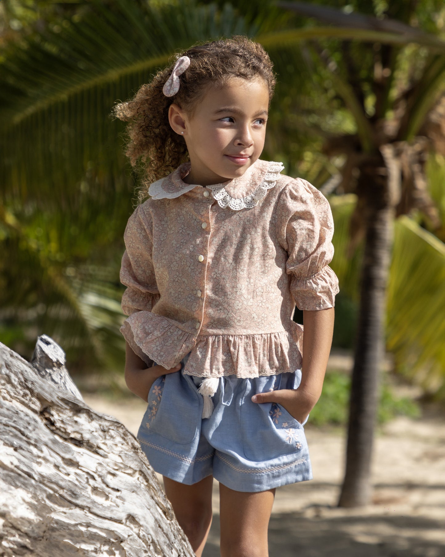 Early Sunday, Iris Blouse in Garden Flowers print, made from Printed Cotton Cambric fabric, featuring relaxed fit with delicate detailing for a timeless and feminine look, shown in a front view of model wearing outdoors