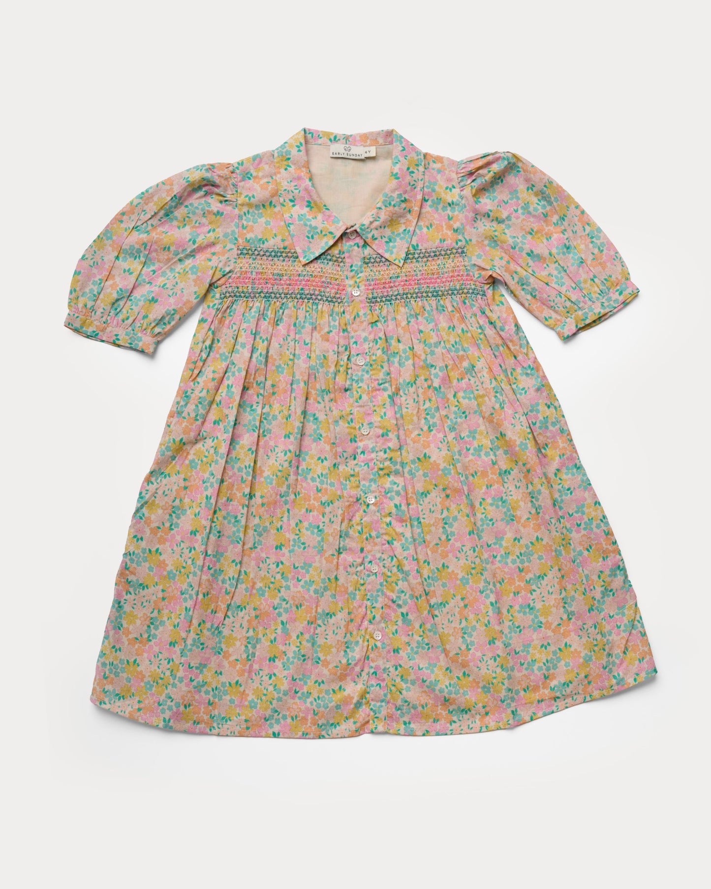 Early Sunday, Jane Dress in Emma Floral Mint color, made from printed 60s cotton cambric fabric, featuring Smocked / embroidered yoke, peter pan collar and puffed short sleeves, shown in a front flat-lay view