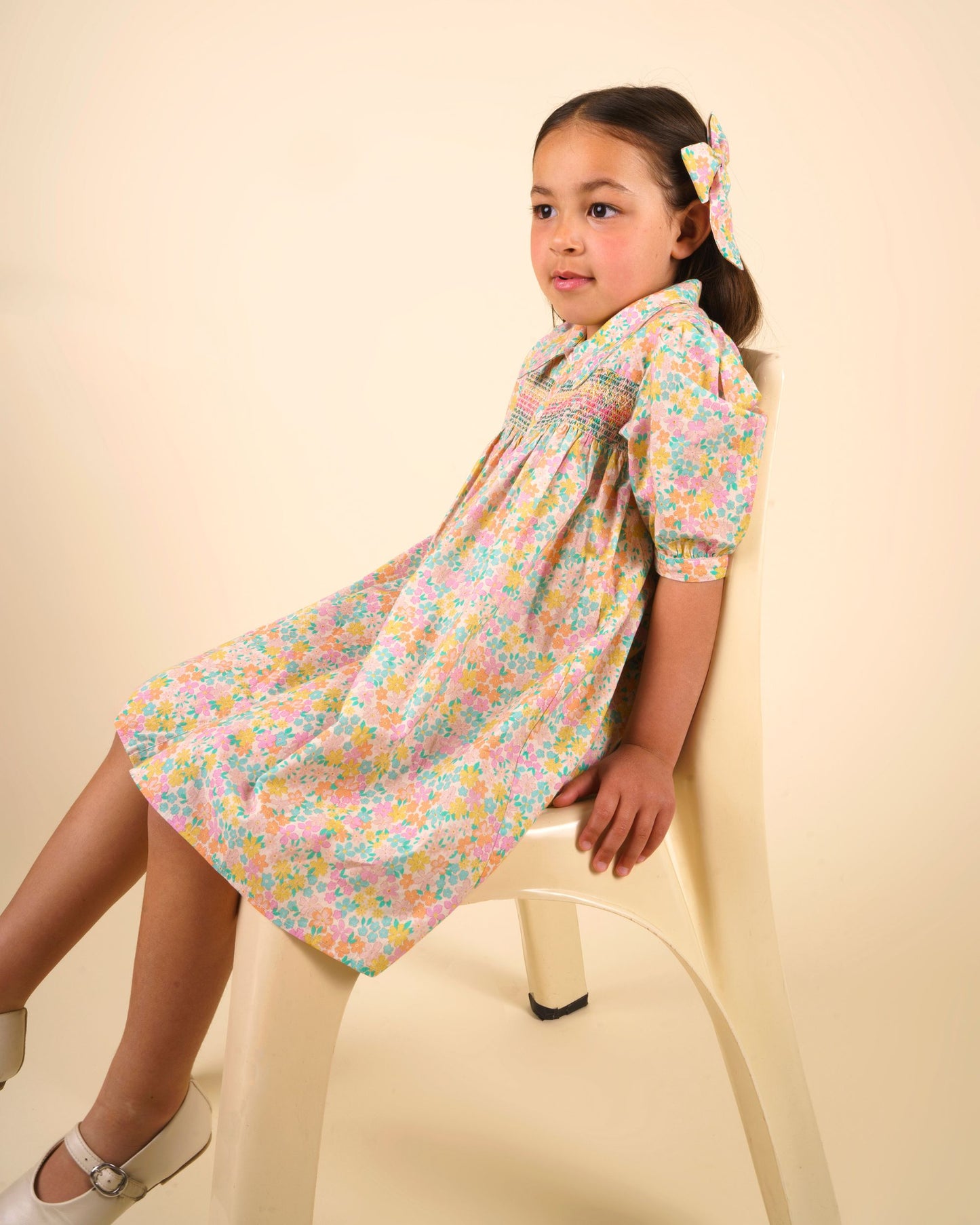 Early Sunday, Jane Dress in Emma Floral Mint color, made from printed 60s cotton cambric fabric, featuring Smocked / embroidered yoke, peter pan collar and puffed short sleeves, shown in a close up shot of model wearing it